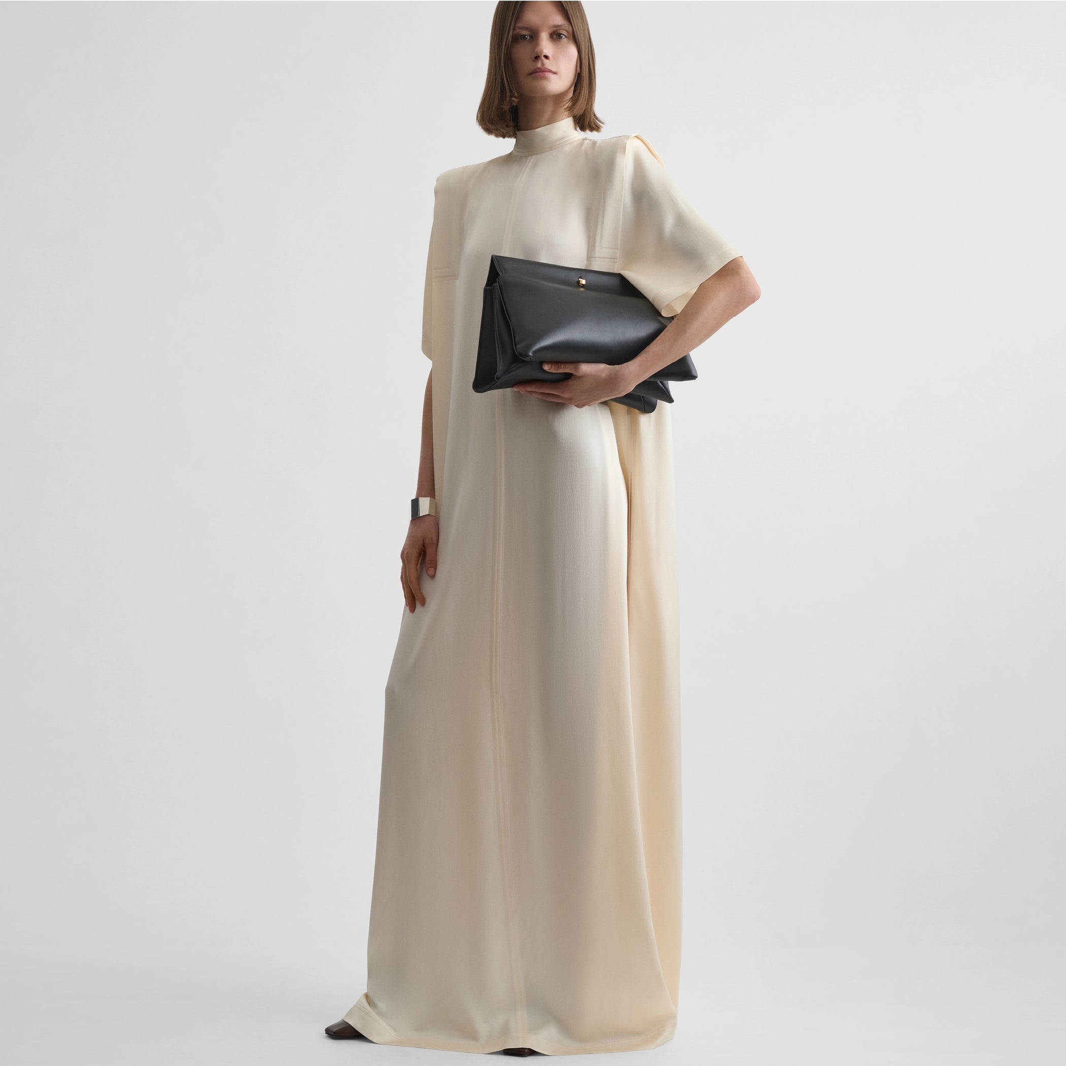 Front full body view of model wearing folded shoulder dress in vanilla satin back crepe