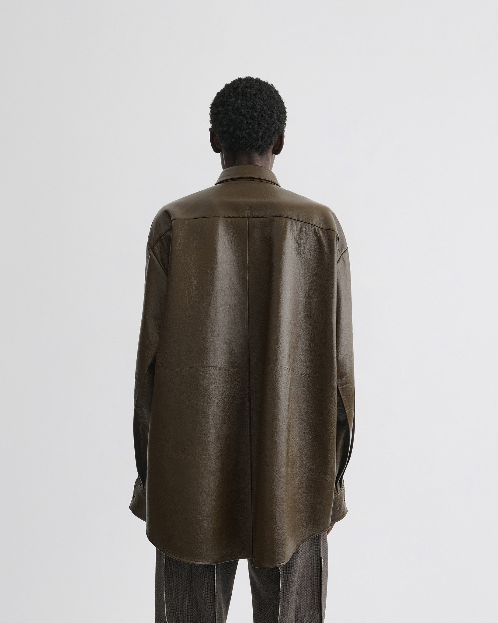 Back view of model wearing overshirt in green bronze leather.
