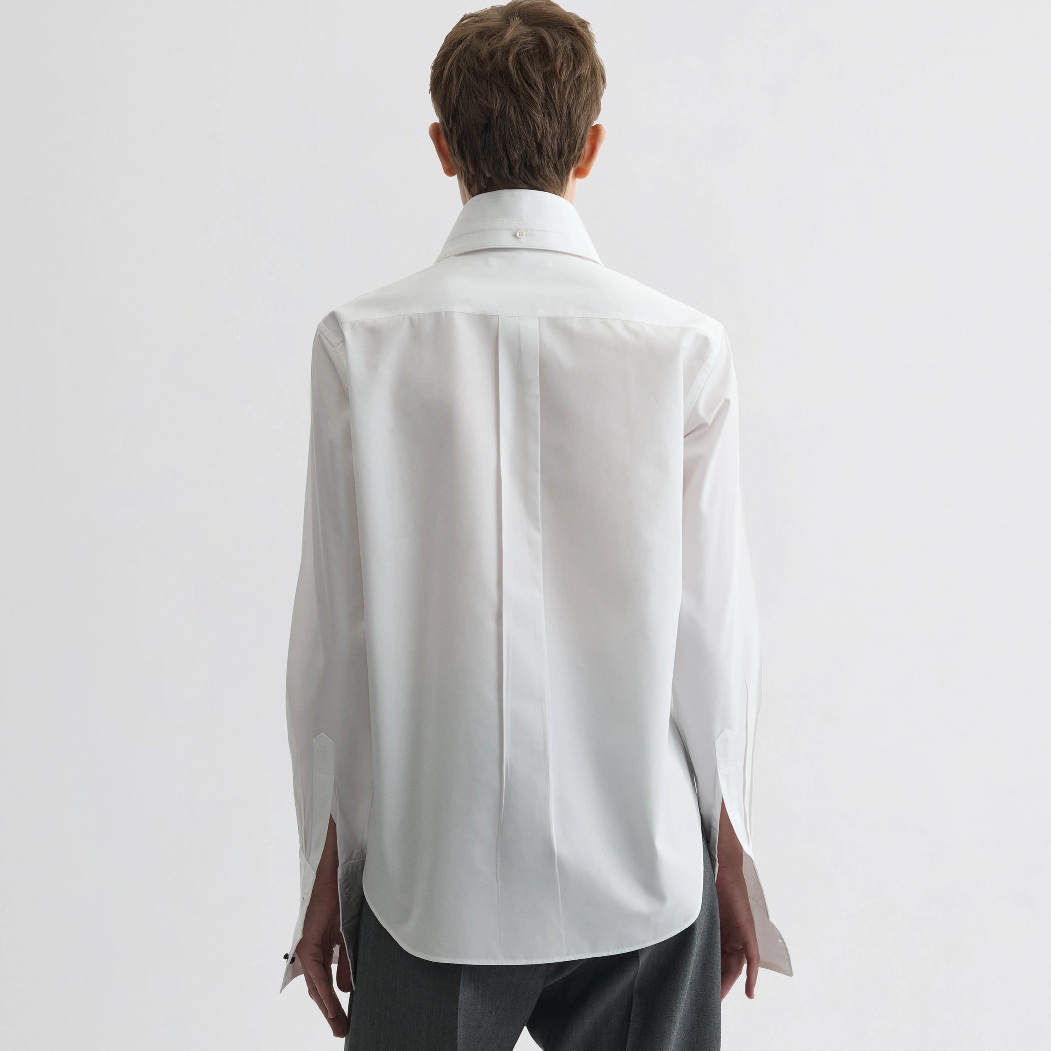 Back view of model wearing tuxedo shirt in white cotton.