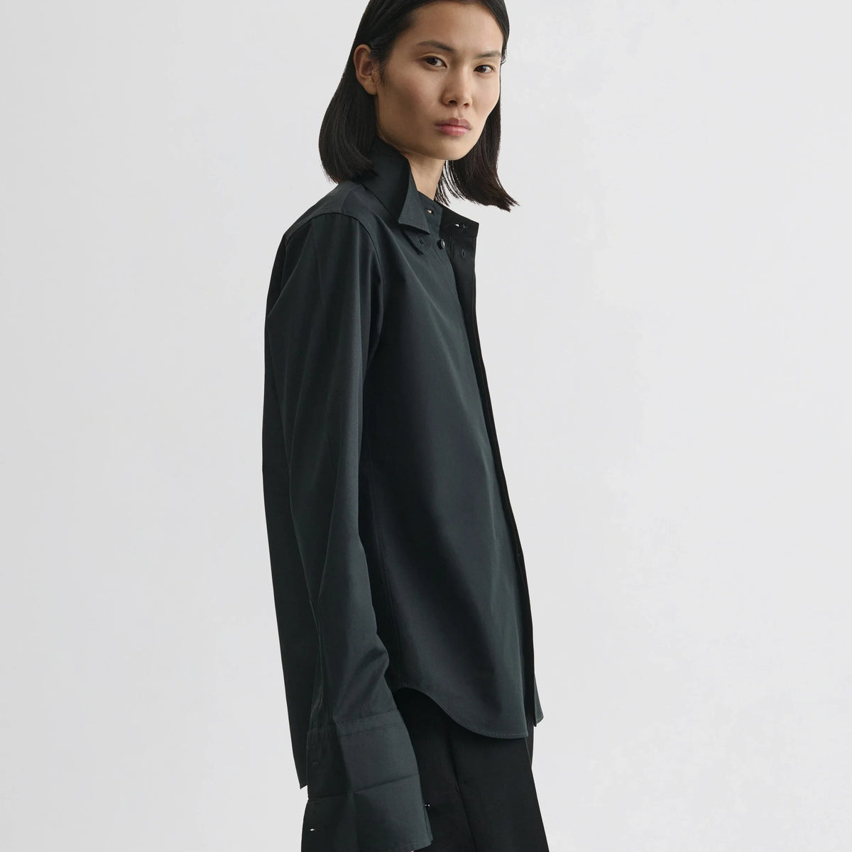 Side view of model wearing tuxedo shirt in black cotton.