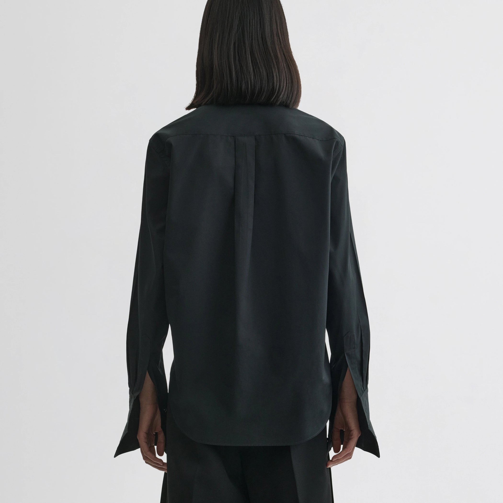 Back view of model wearing tuxedo shirt in black cotton.