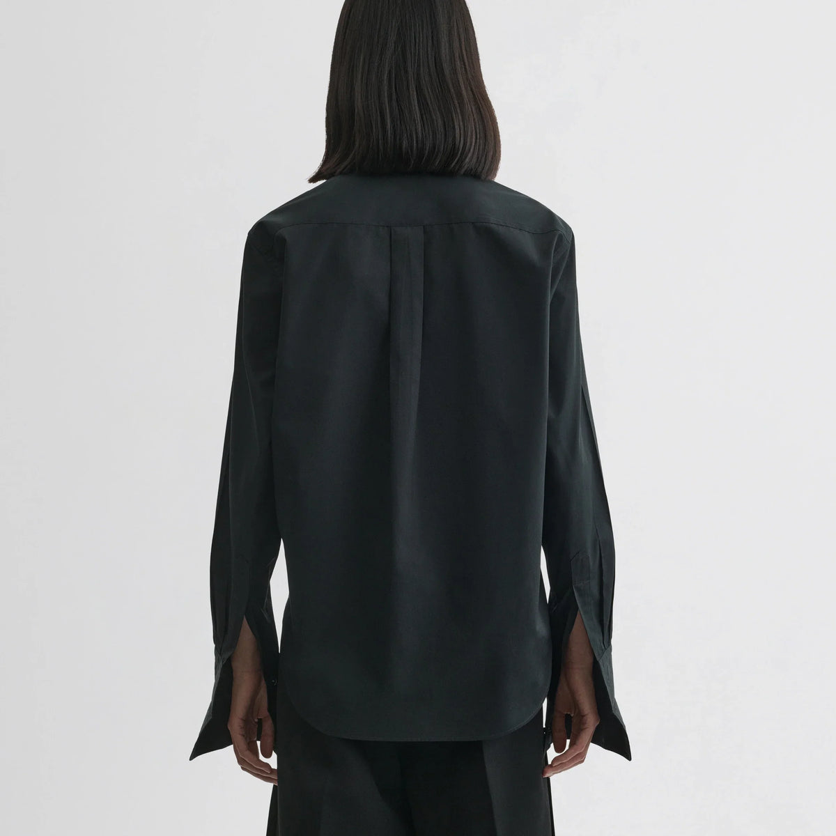 Back view of model wearing tuxedo shirt in black cotton.