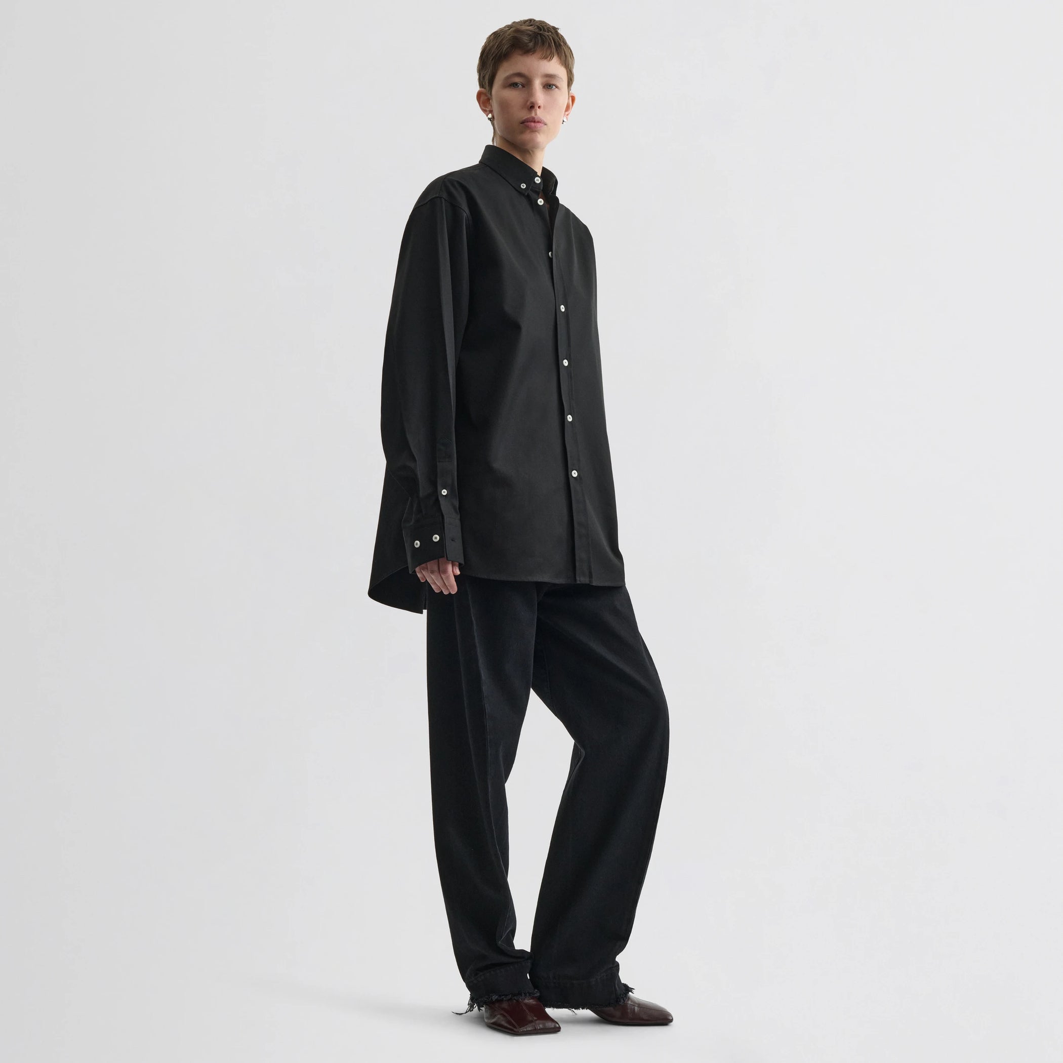 Front view of model wearing button collar shirt in black cotton.