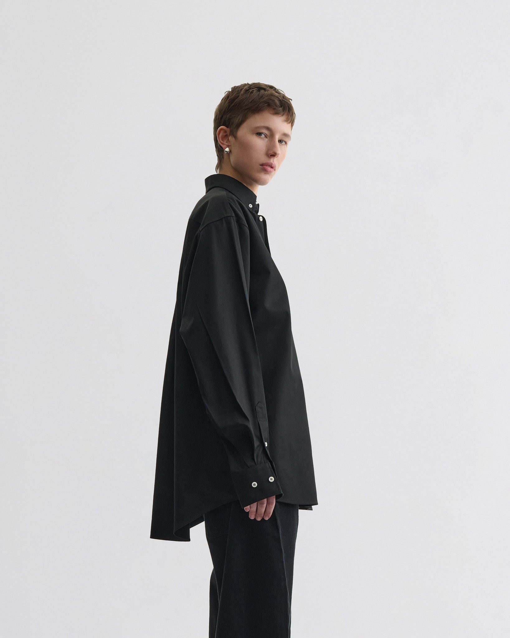 Side view of model wearing button collar shirt in midnight pinstripe cotton.