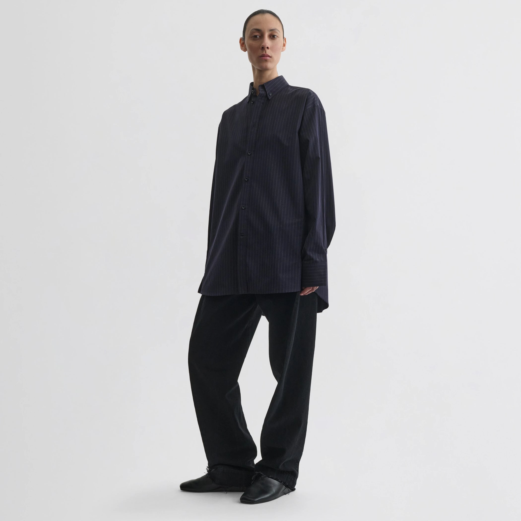 Front view of model wearing button collar shirt in midnight pinstripe cotton.