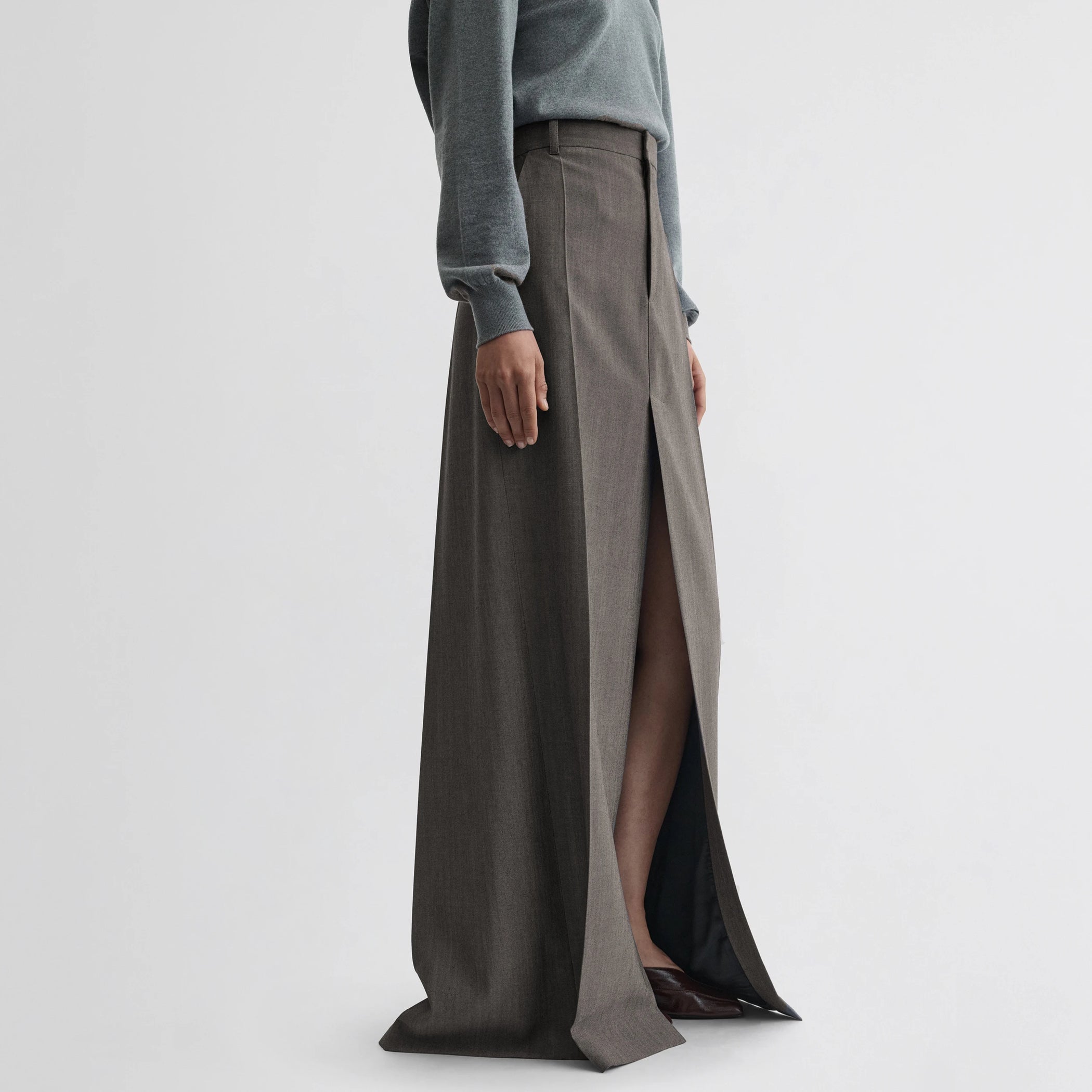 Side view of model wearing double slit tailored skirt in dark taupe wool.