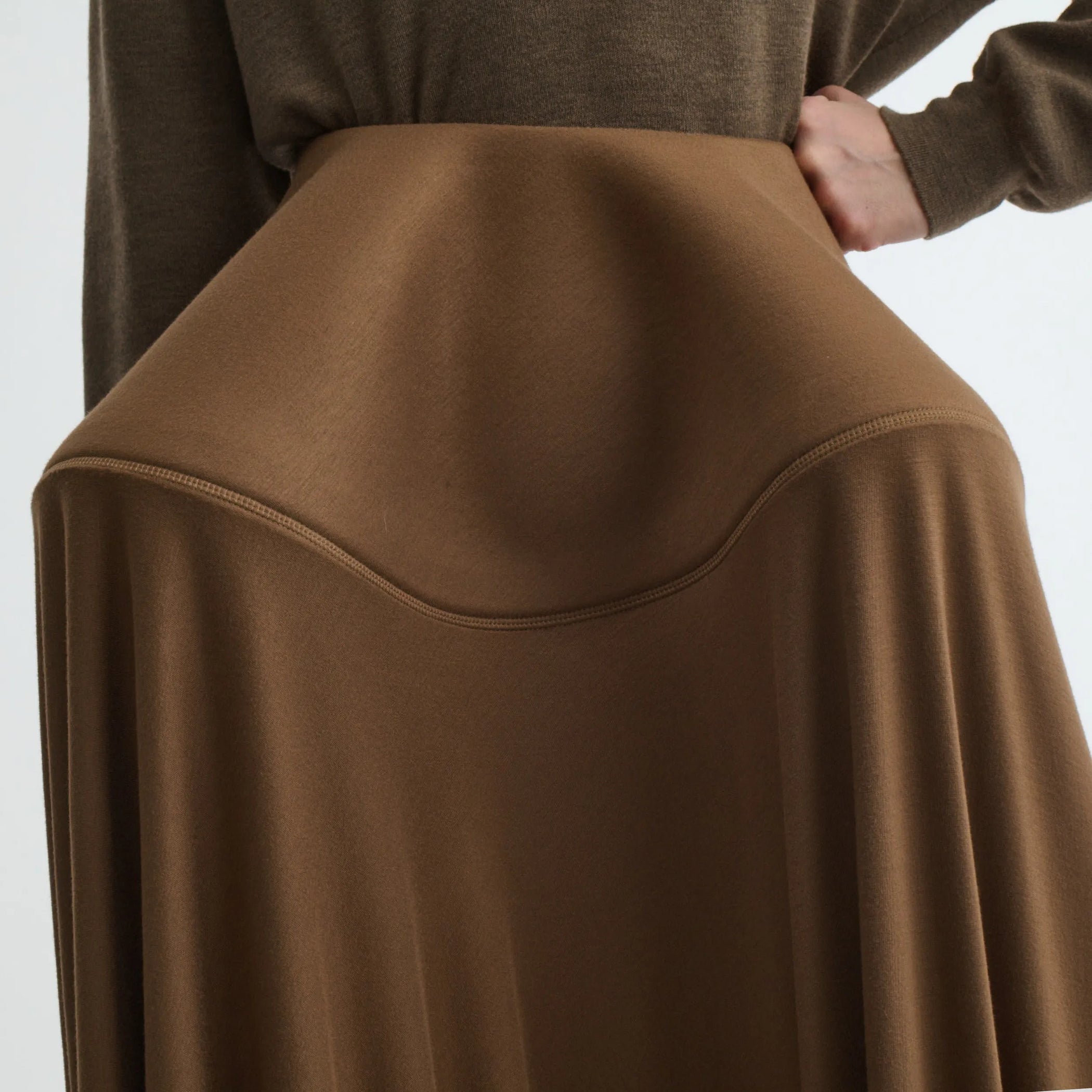 Close up detail view of sculptural skirt in toffee jersey.