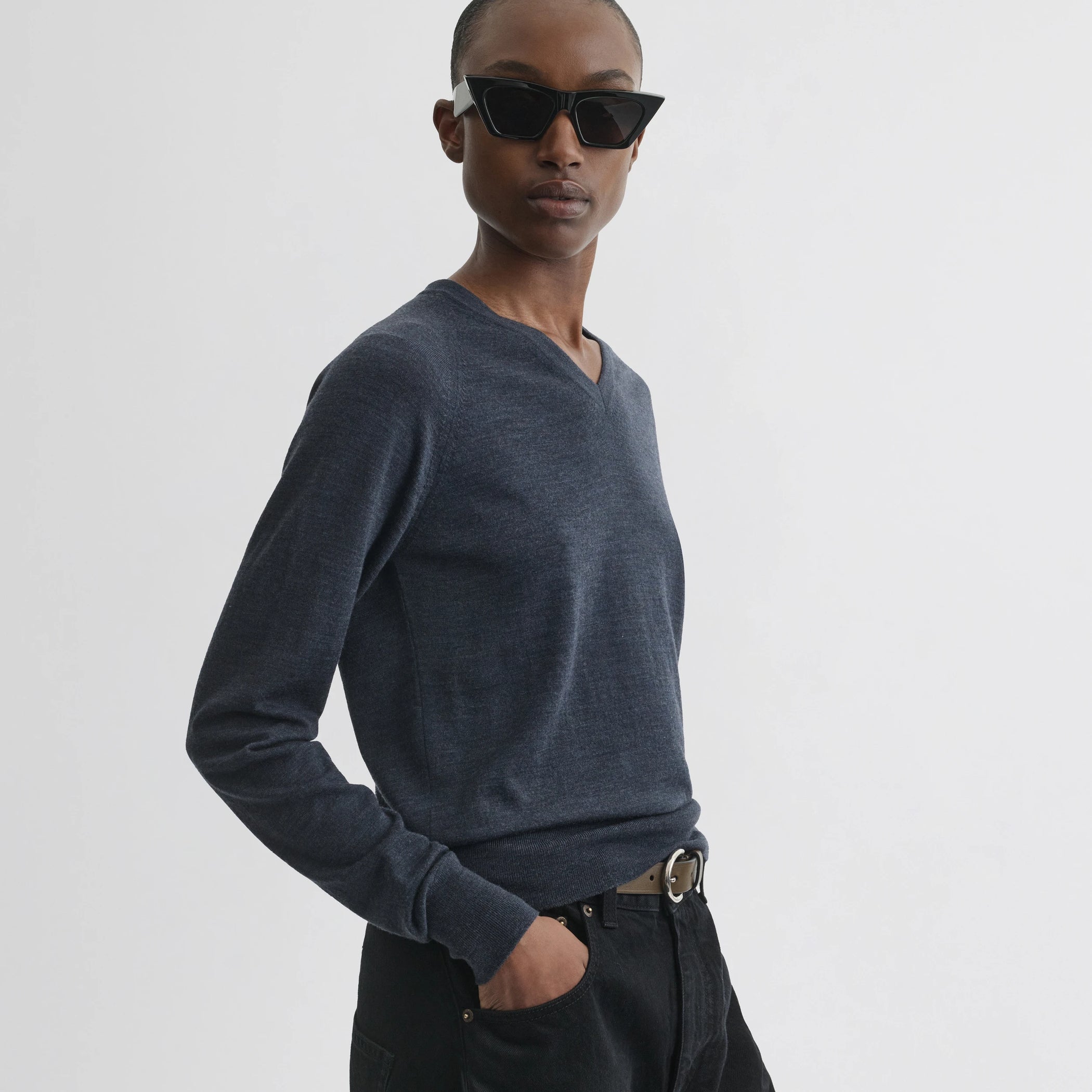 Side view of model wearing shrunk v-neck in dark blue melange wool.