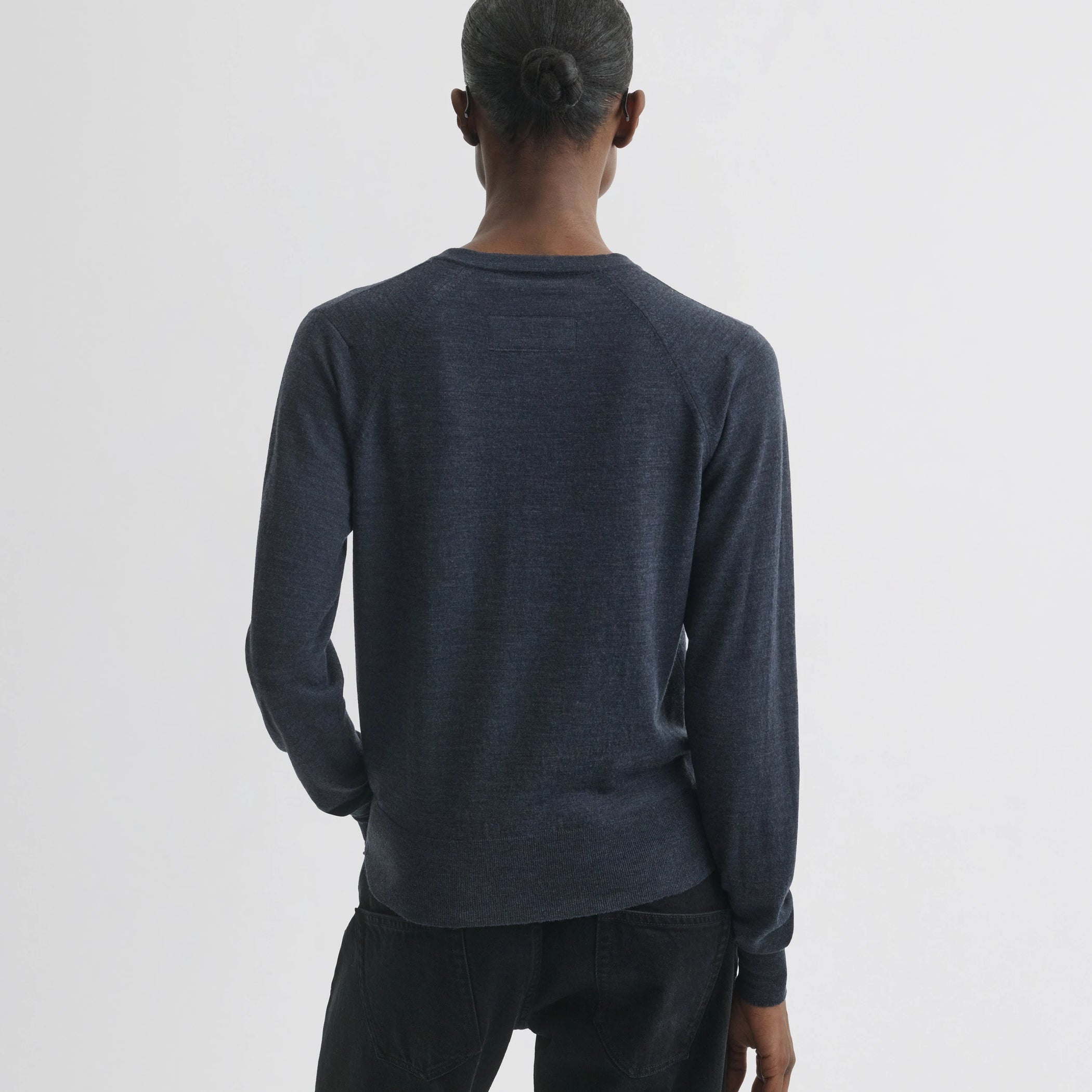 Back view of model wearing shrunk v-neck in dark blue melange wool.
