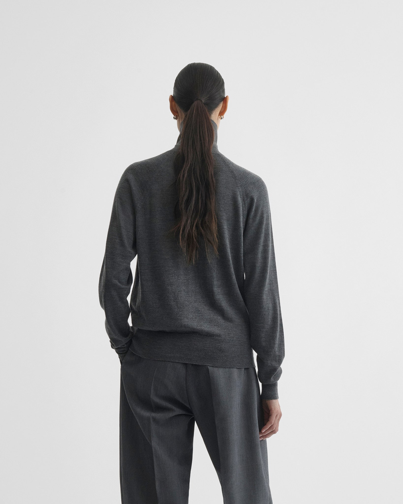Back view of model wearing high neck jumper in anthracite-melange wool