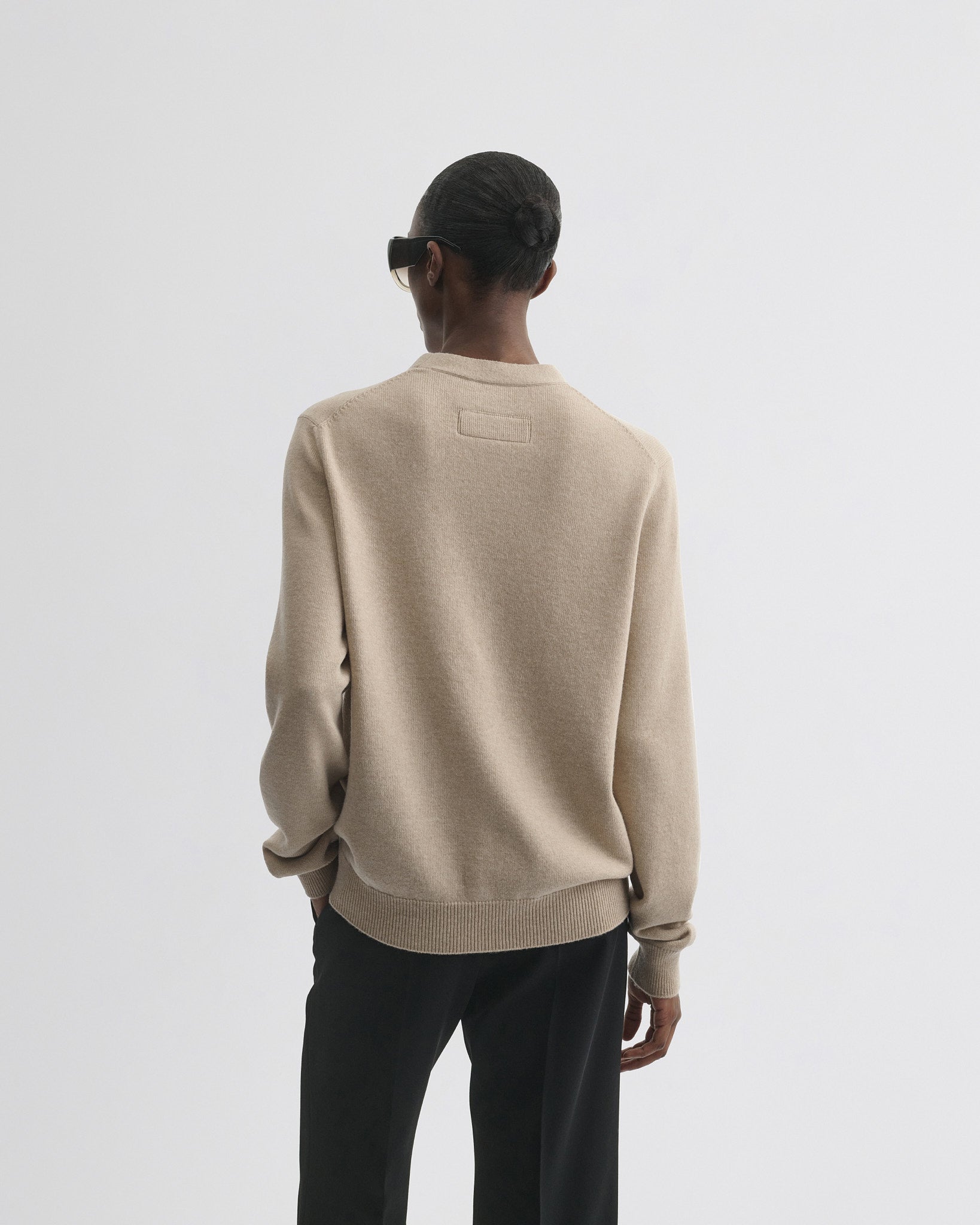 Back view of model wearing easy v-neck sweater in beige wool cashmere.