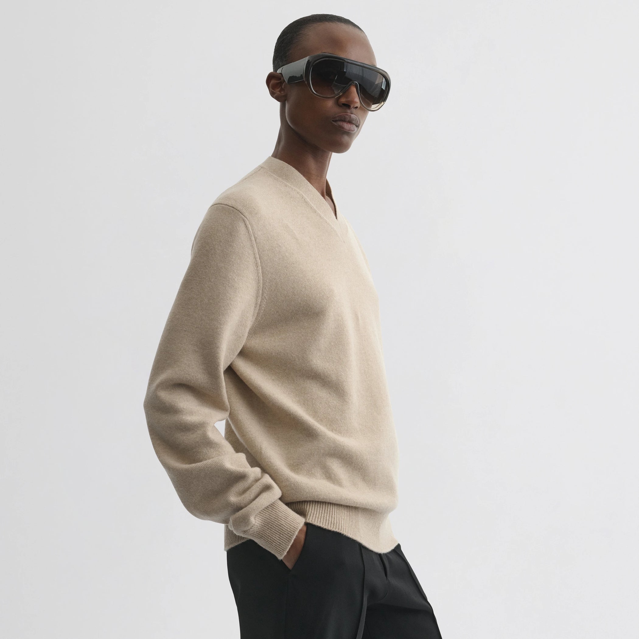 Side view of model wearing easy v-neck sweater in beige wool cashmere.