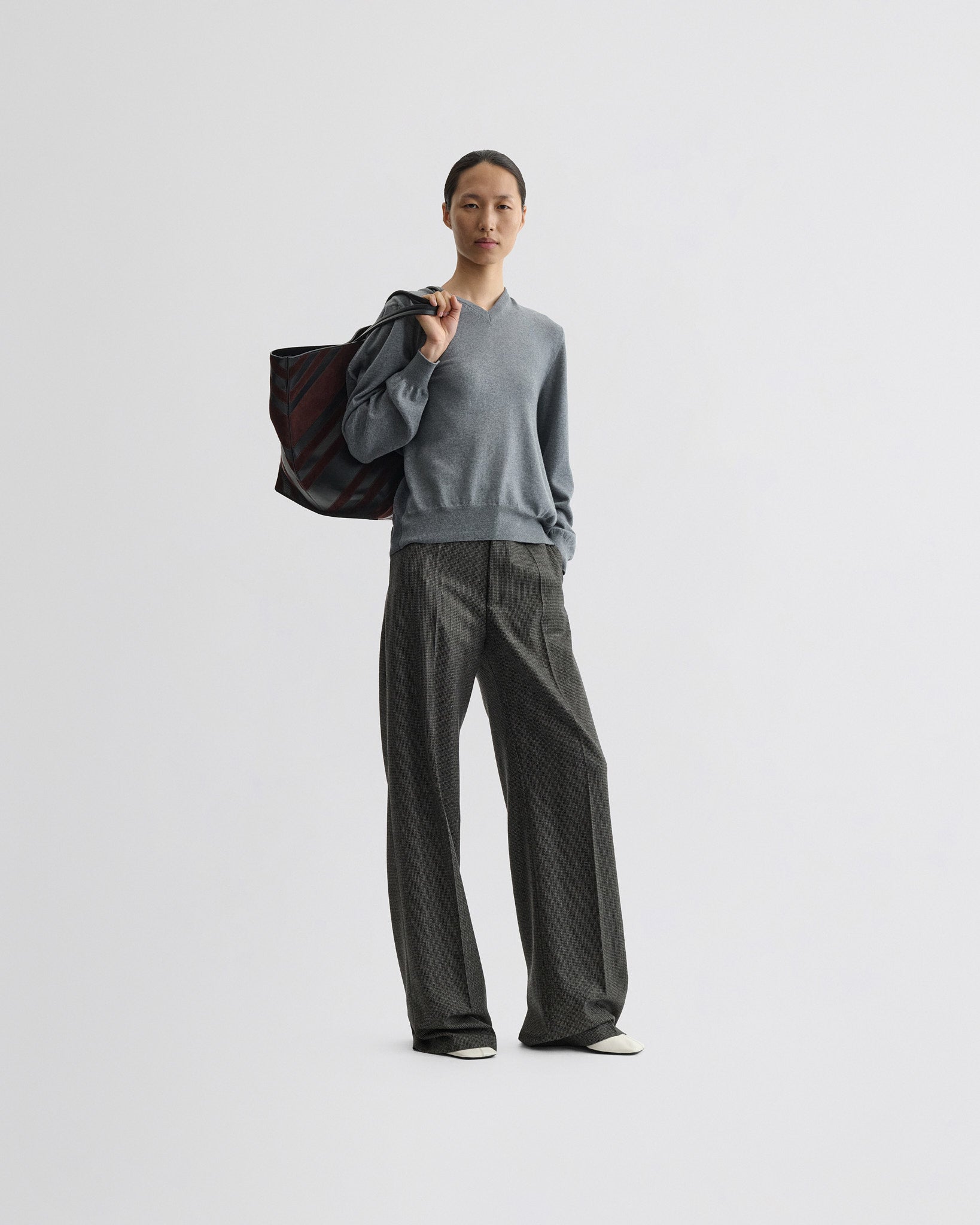 Front view of model wearing backed v-neck sweater in light grey wool.