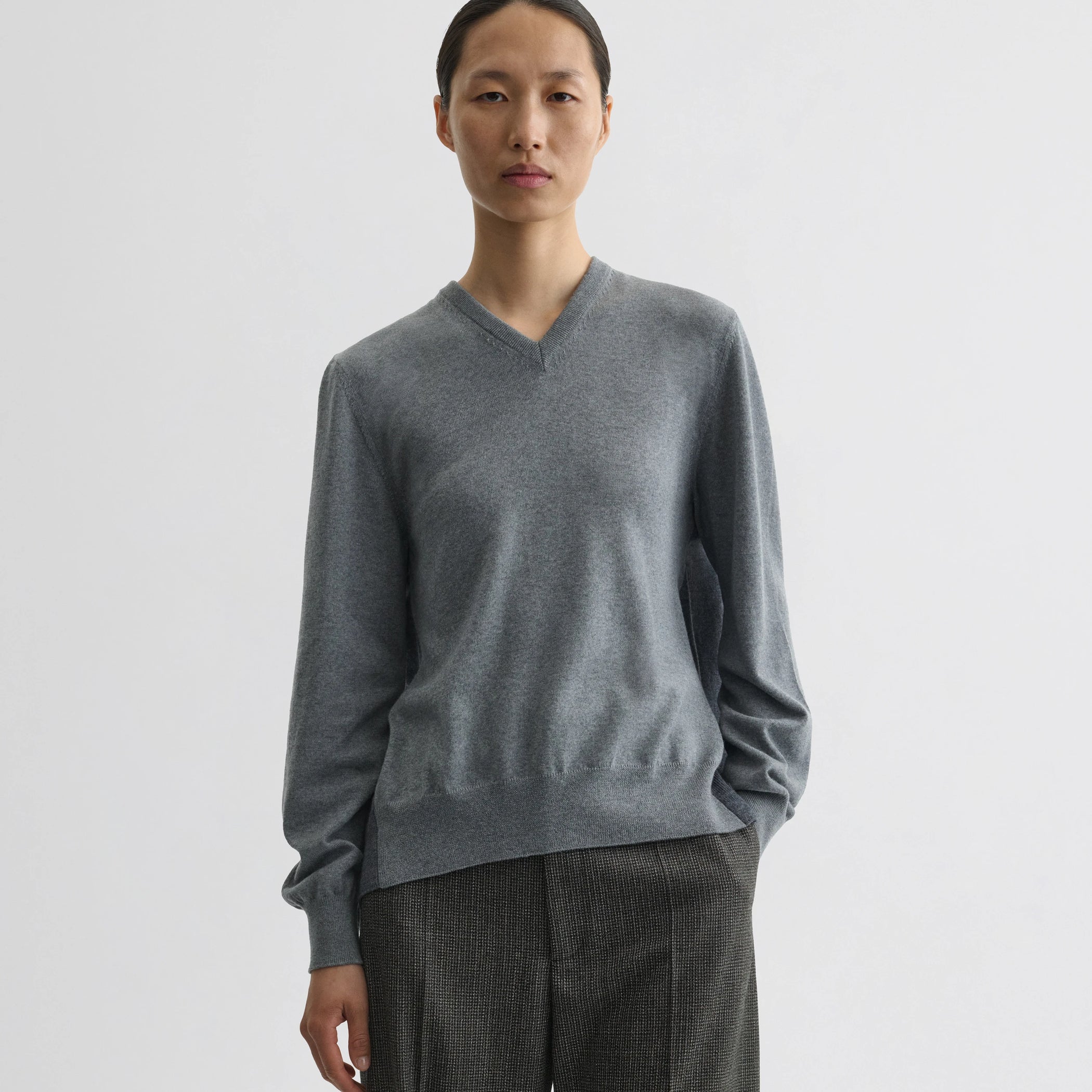 Front view of model wearing backed v-neck sweater in light grey wool.