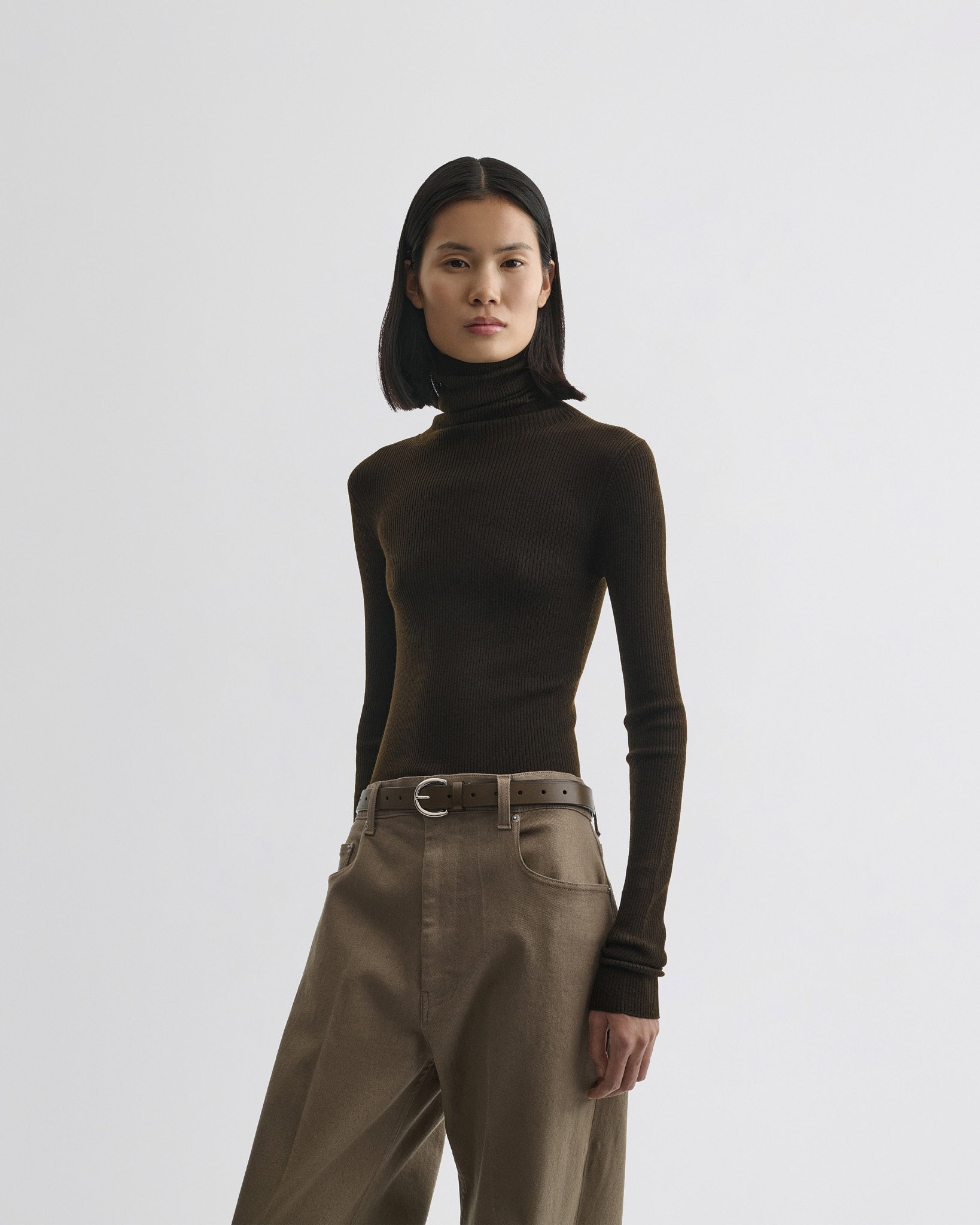 Front view of model wearing fine rib high neck top in dark khaki wool.