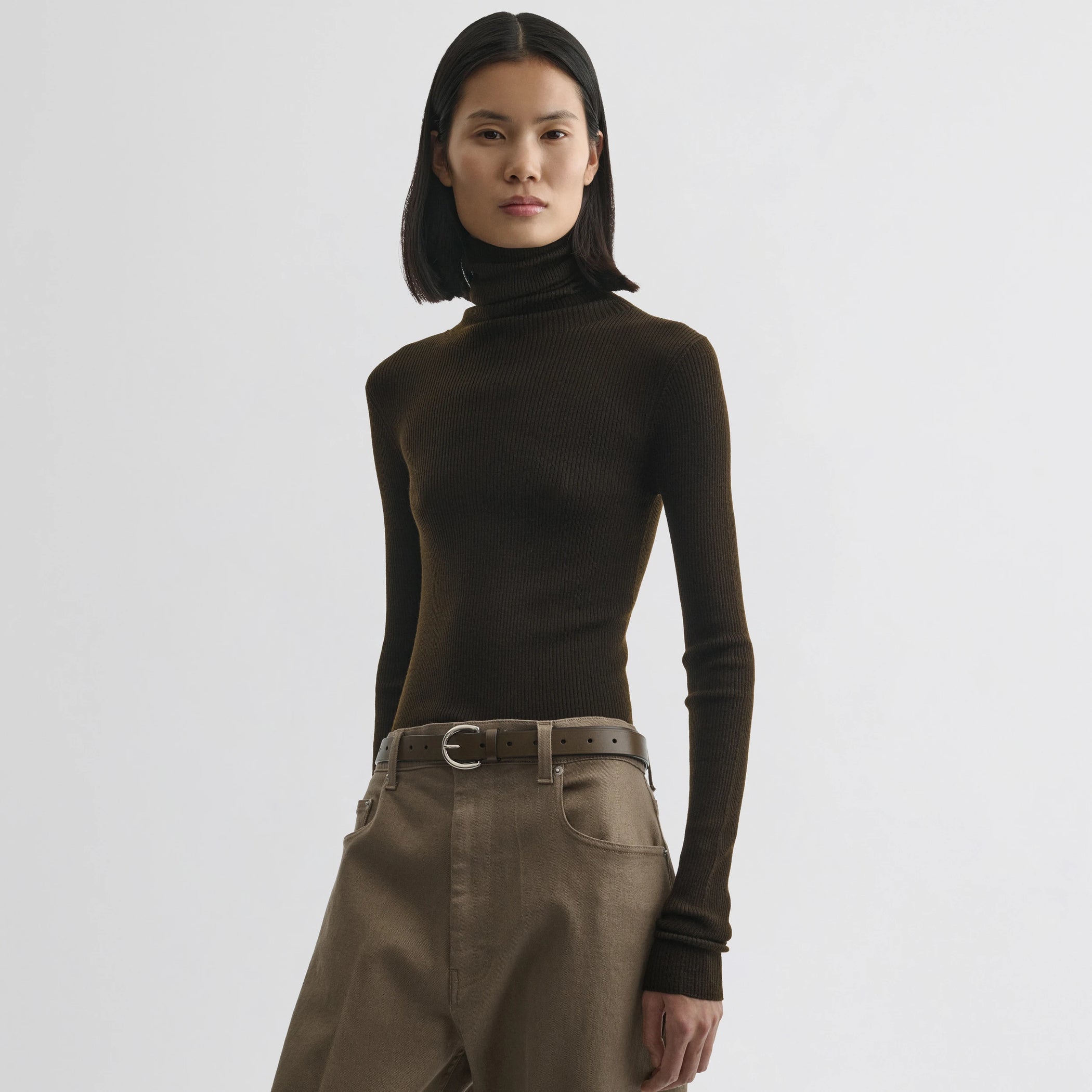 Front view of model wearing fine rib high neck top in dark khaki wool.