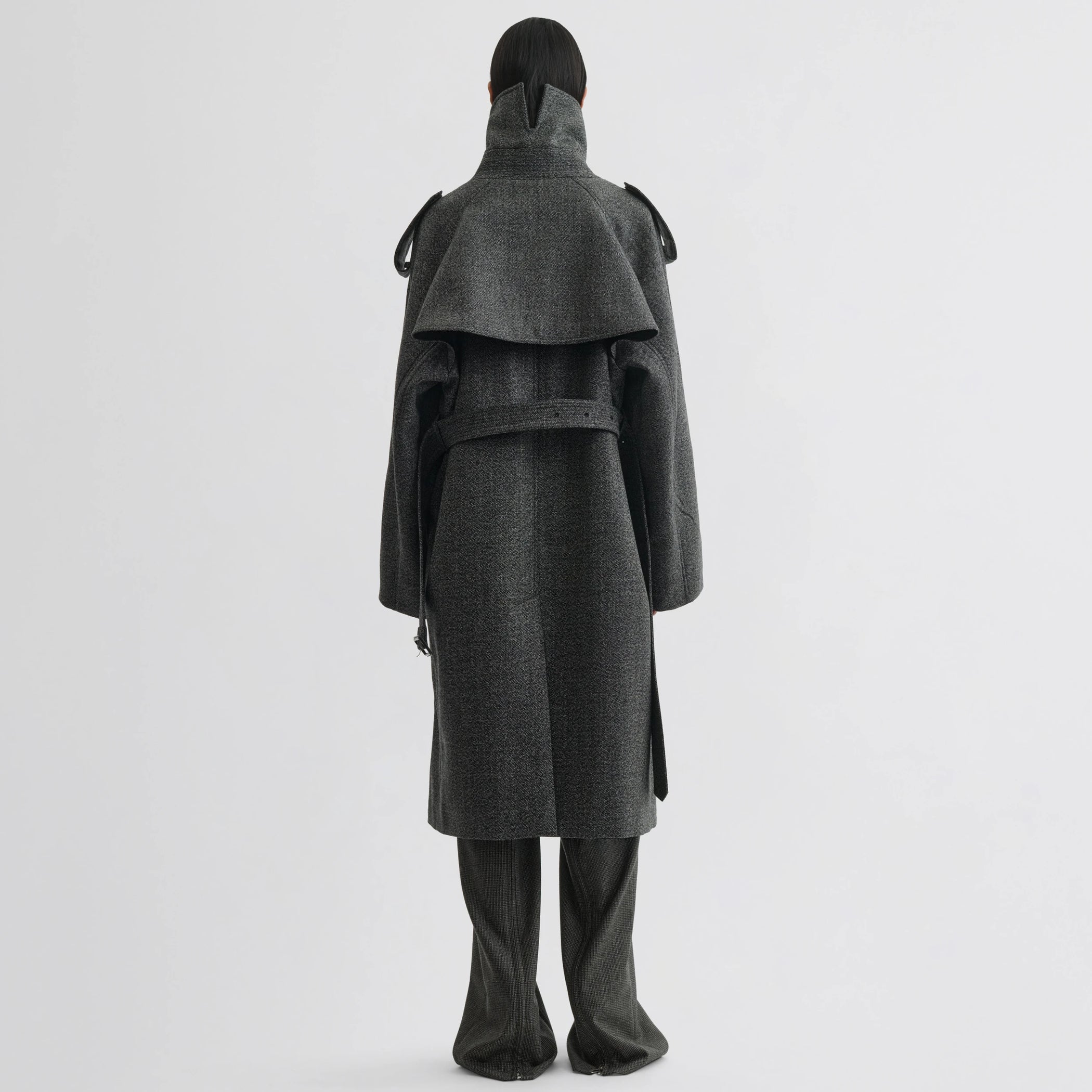 Back view of model wearing padded trench coat in salt and pepper wool.