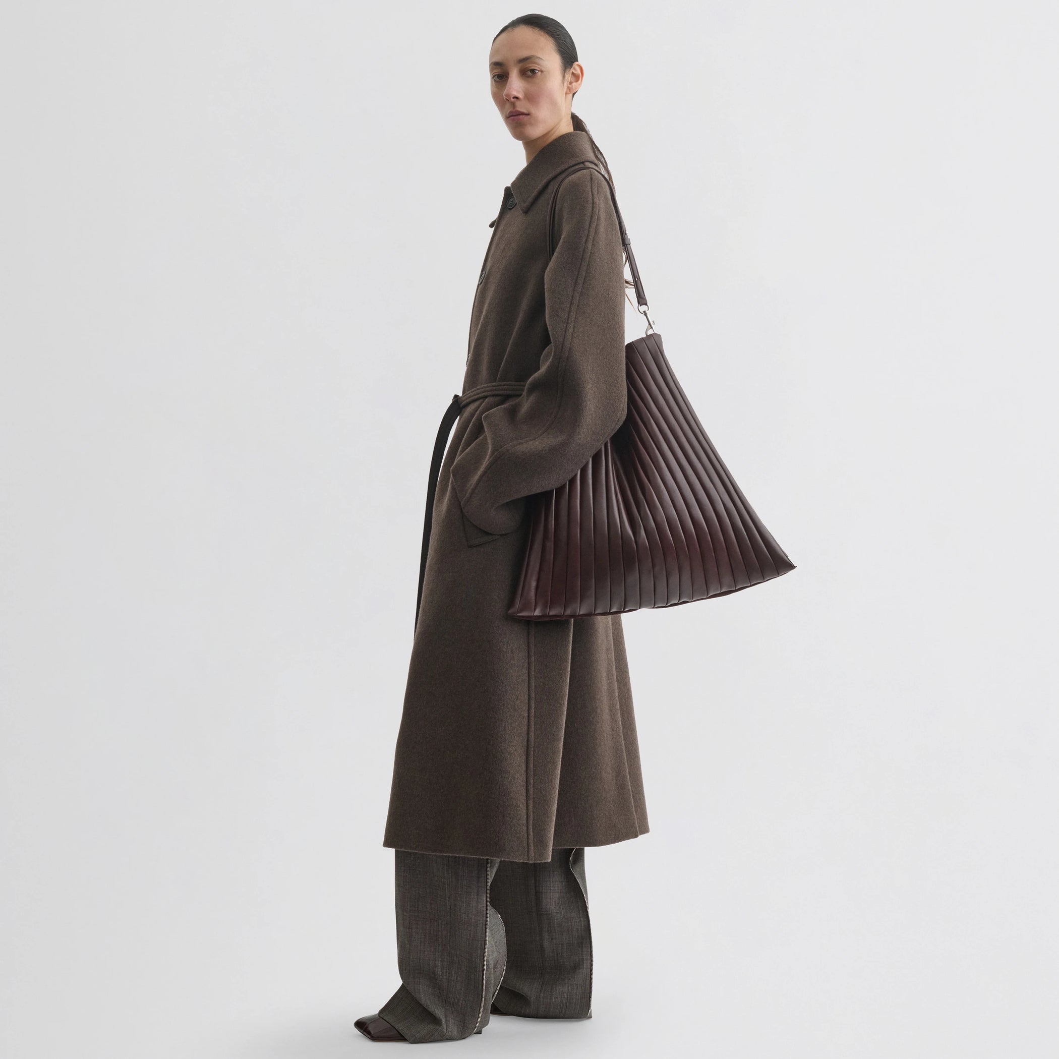 Side view of model wearing curve shoulder coat in brown cashmere.