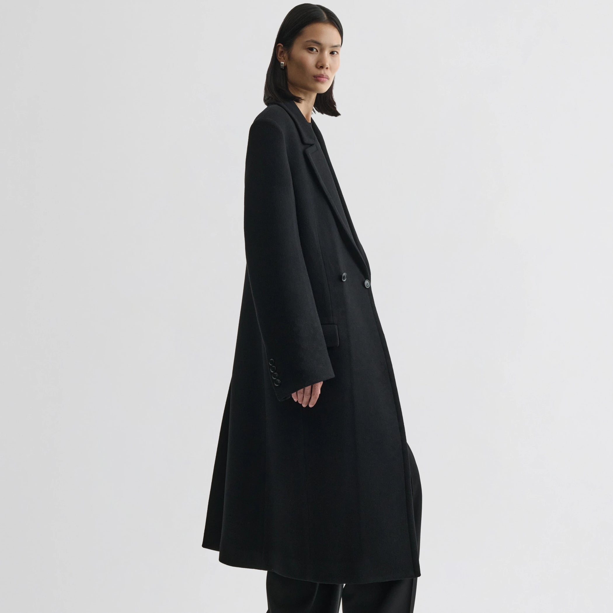 Side view of model wearing classic coat in black cashmere.