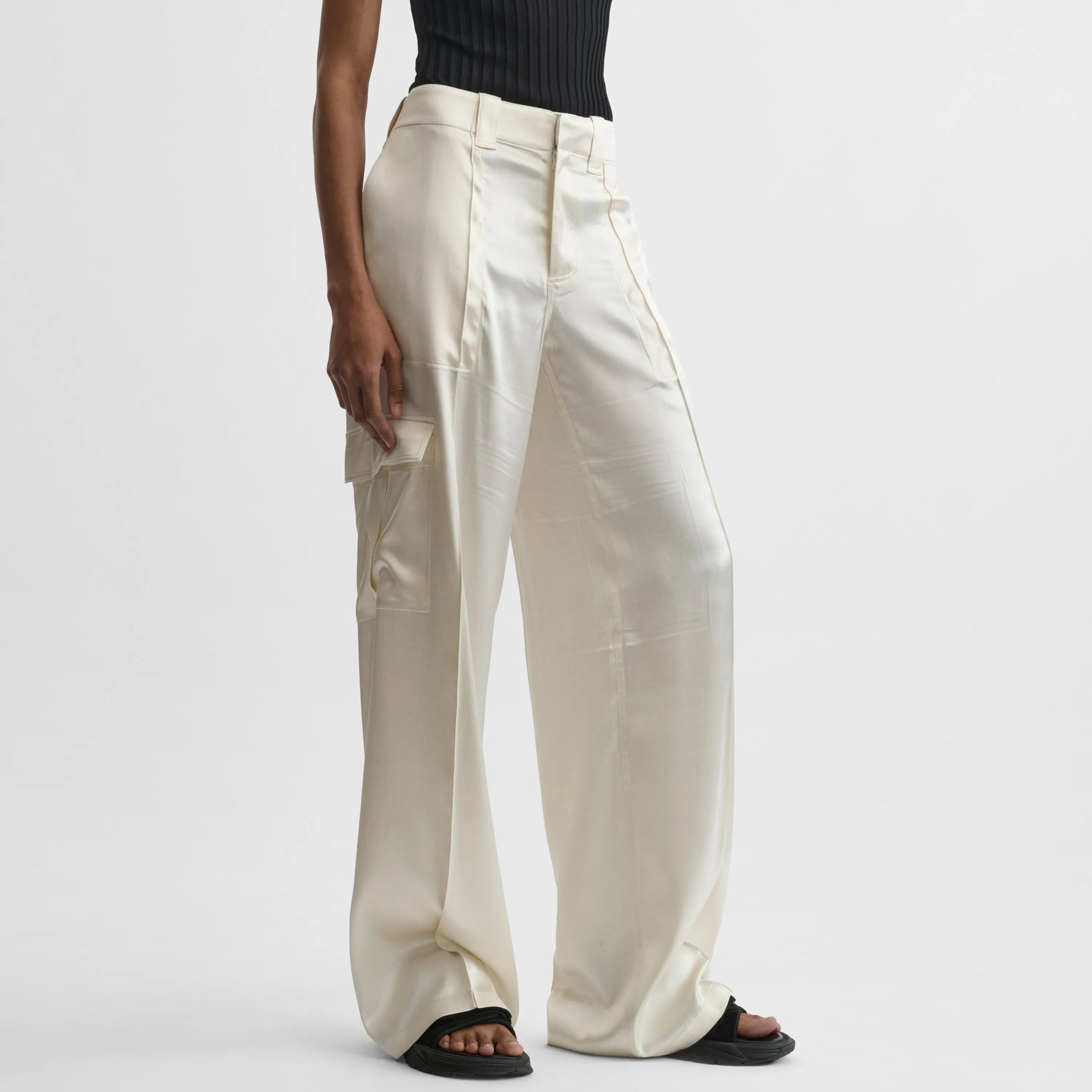 Front view of model wearing liquid cargo trousers in cream silk satin.