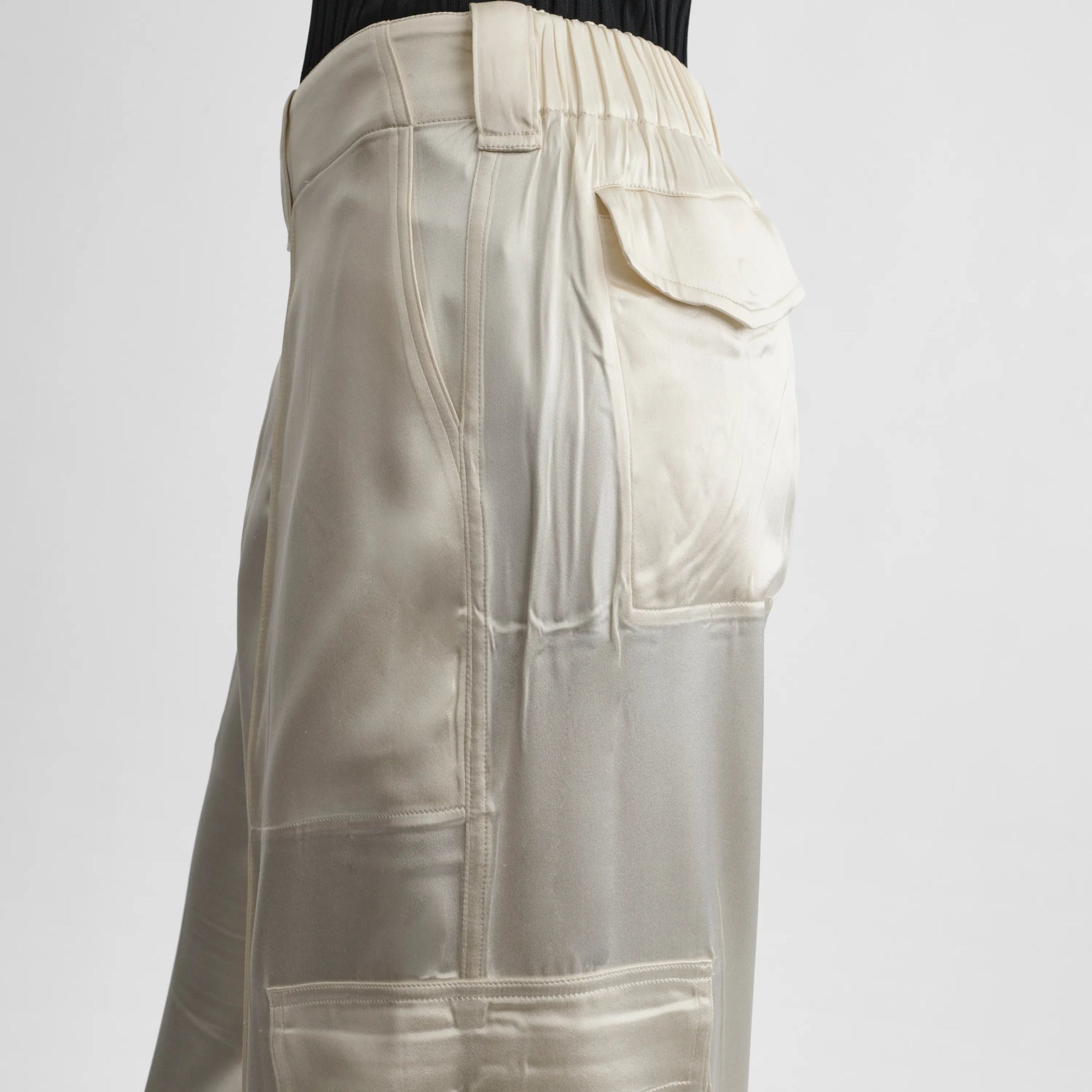 Close up detail view of liquid cargo trousers in cream silk satin.