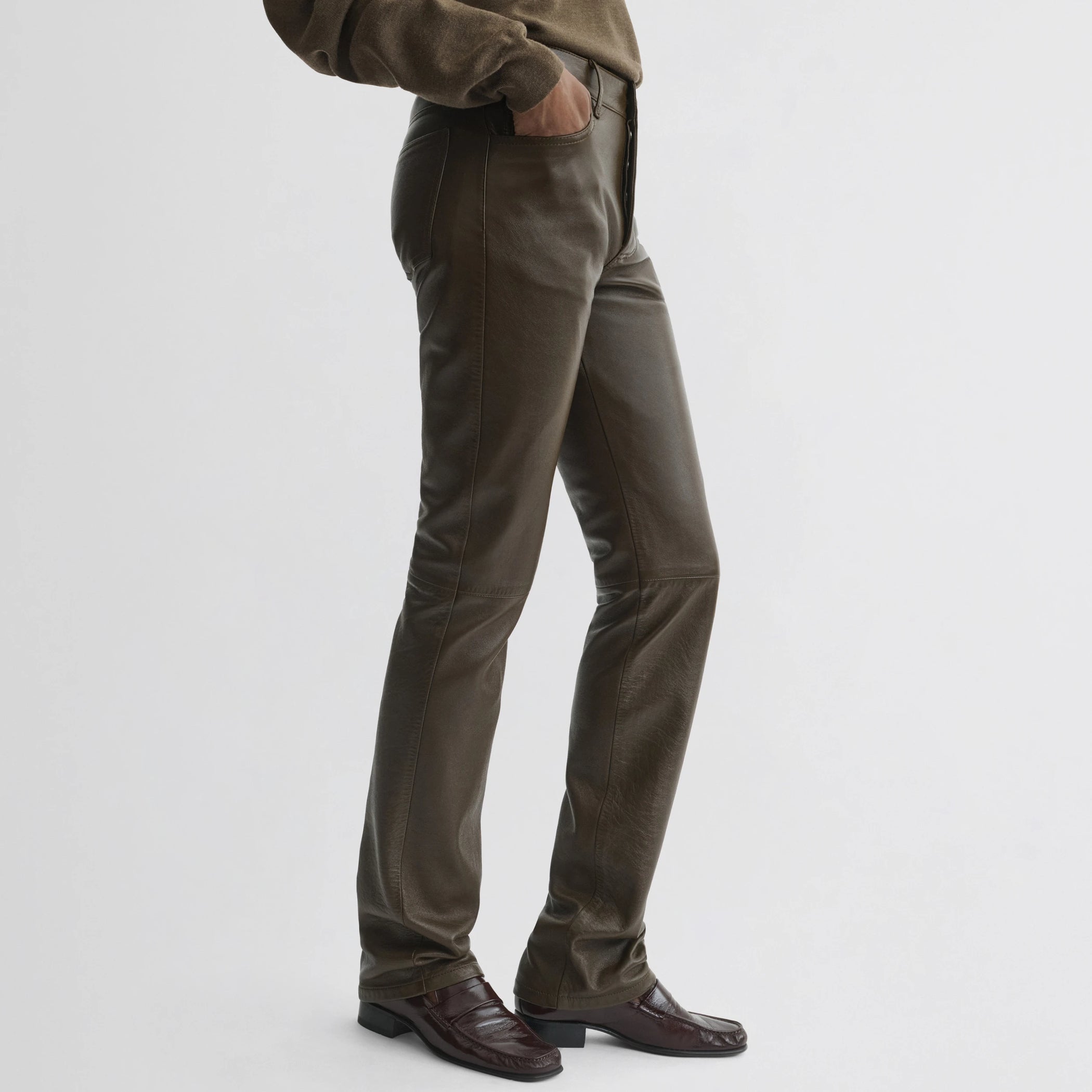 Side view of model wearing straight leg jeans in green bronze leather.