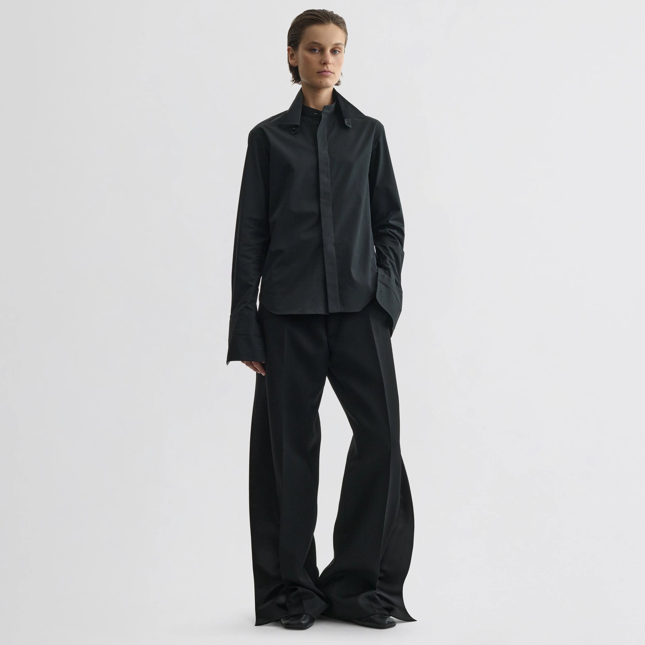 Front view of model wearing split tux trousers in black wool.