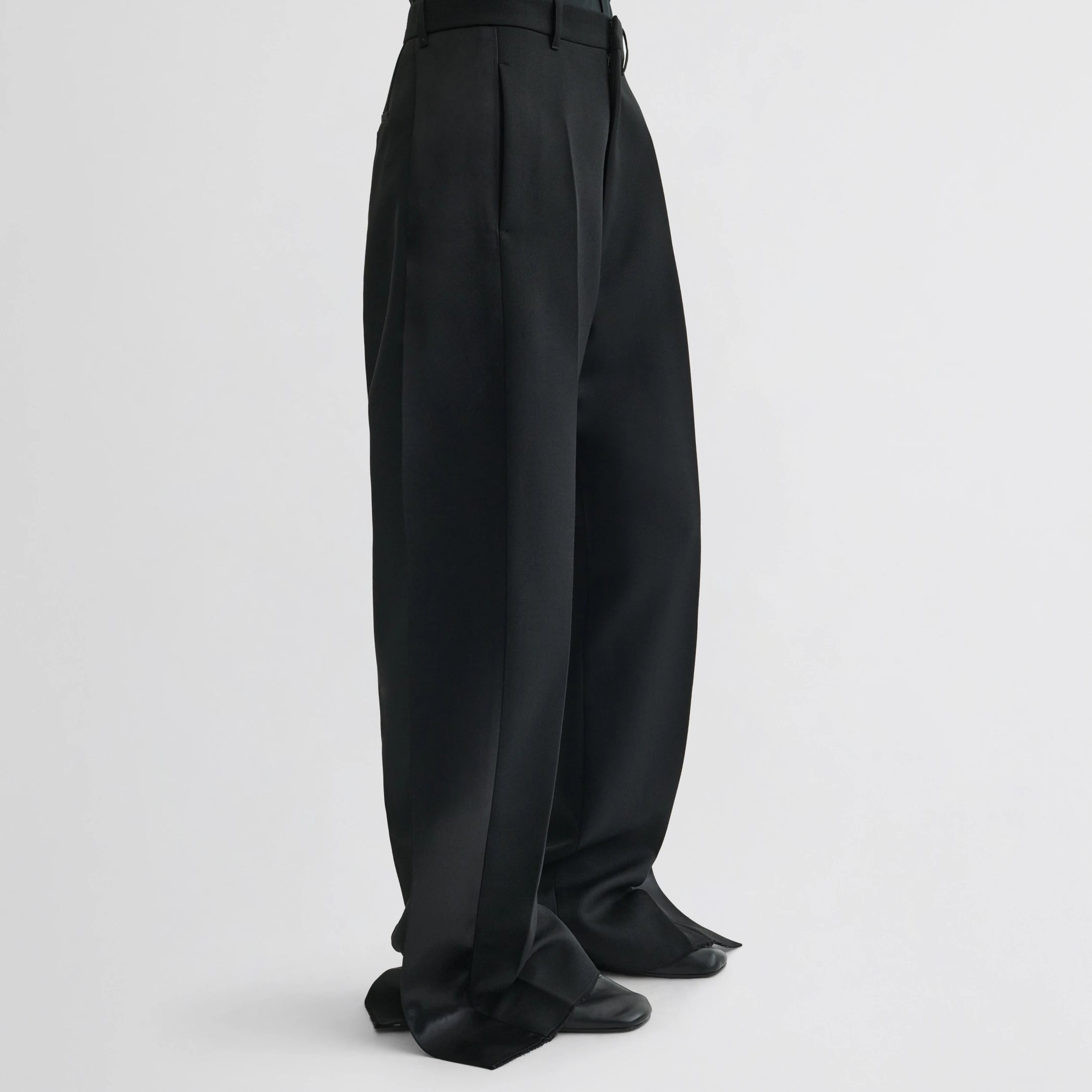 Side view of model wearing split tux trousers in black wool.