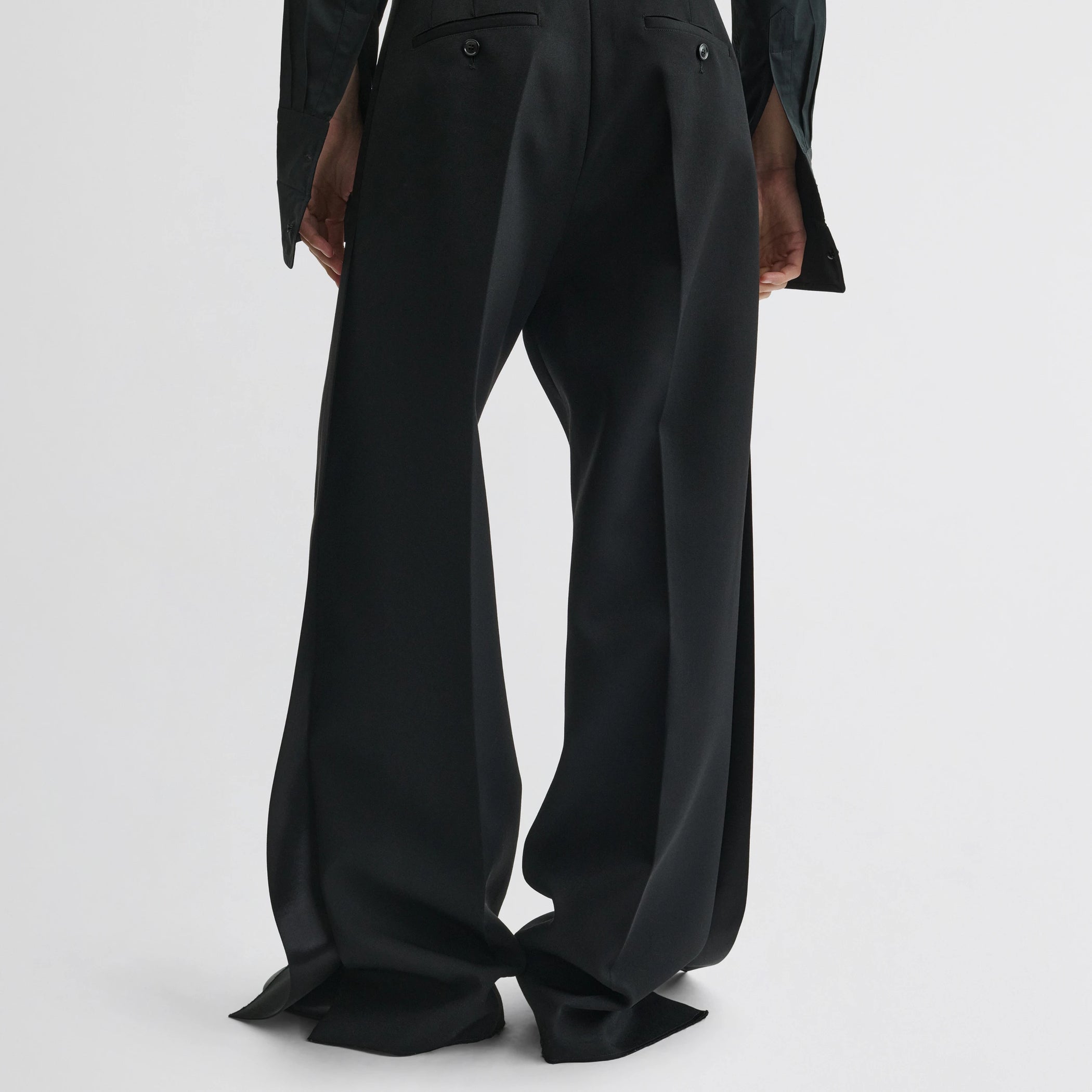 Back view of model wearing split tux trousers in black wool.