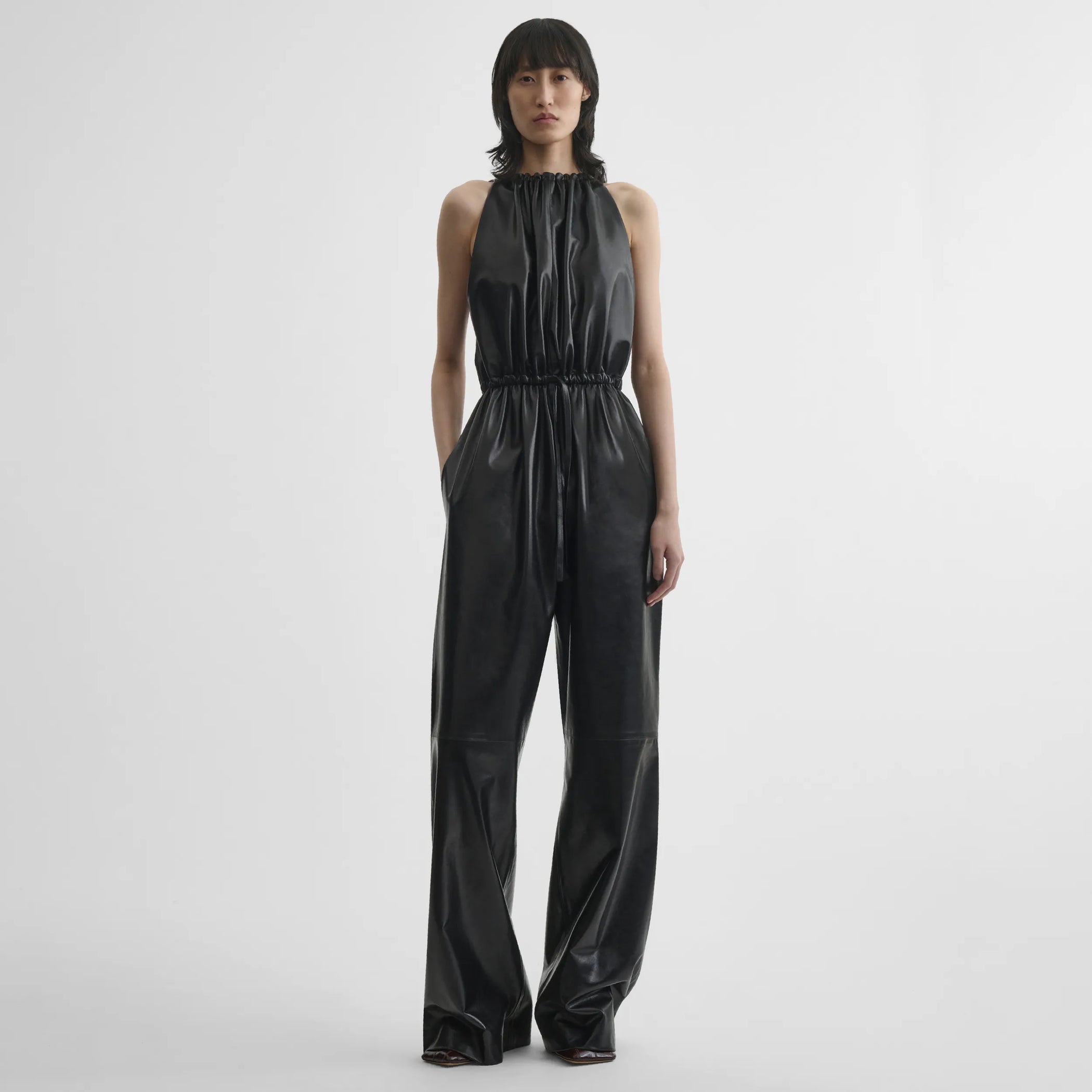 Front view of model wearing drawstring jumpsuit in black leather.