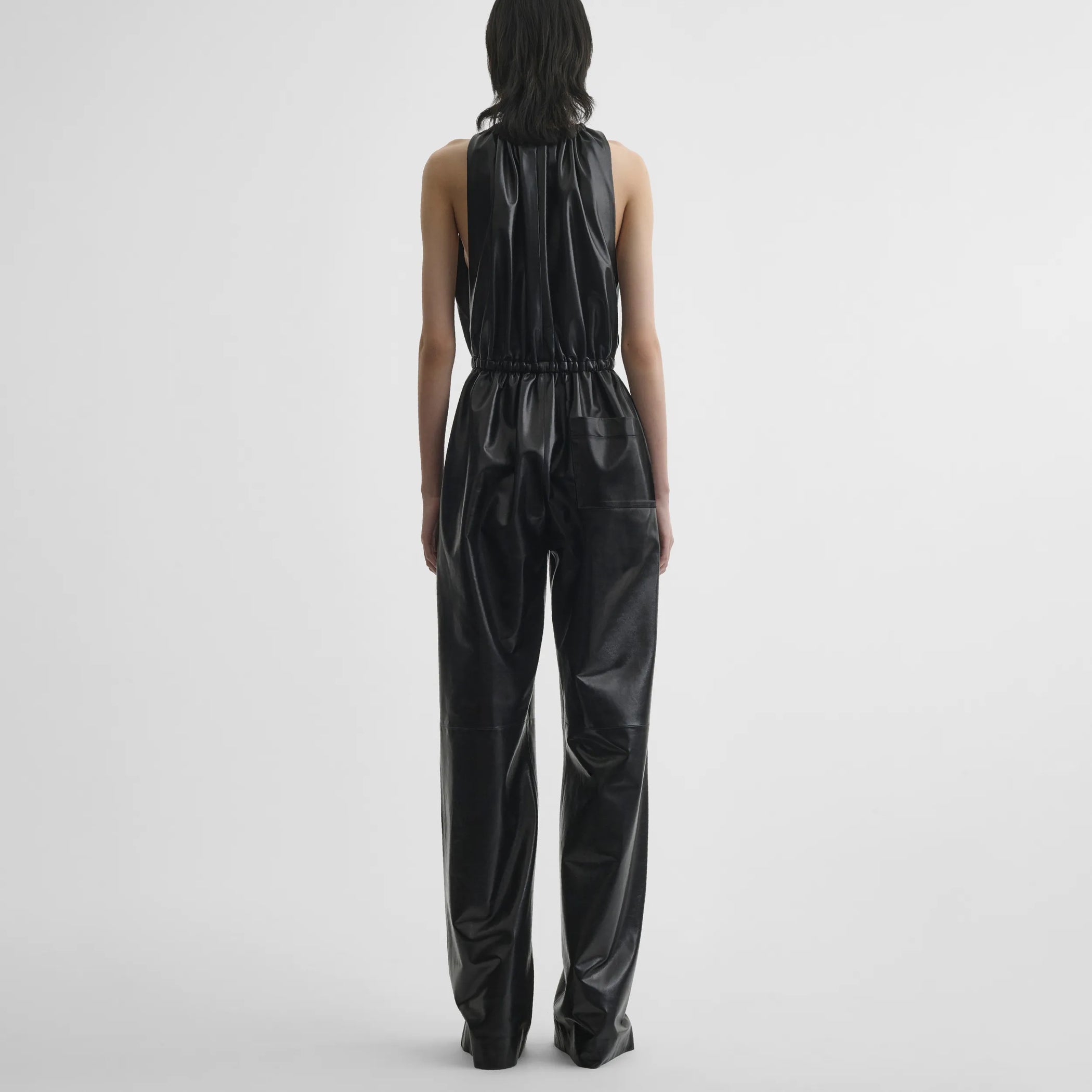Back view of model wearing drawstring jumpsuit in black leather.