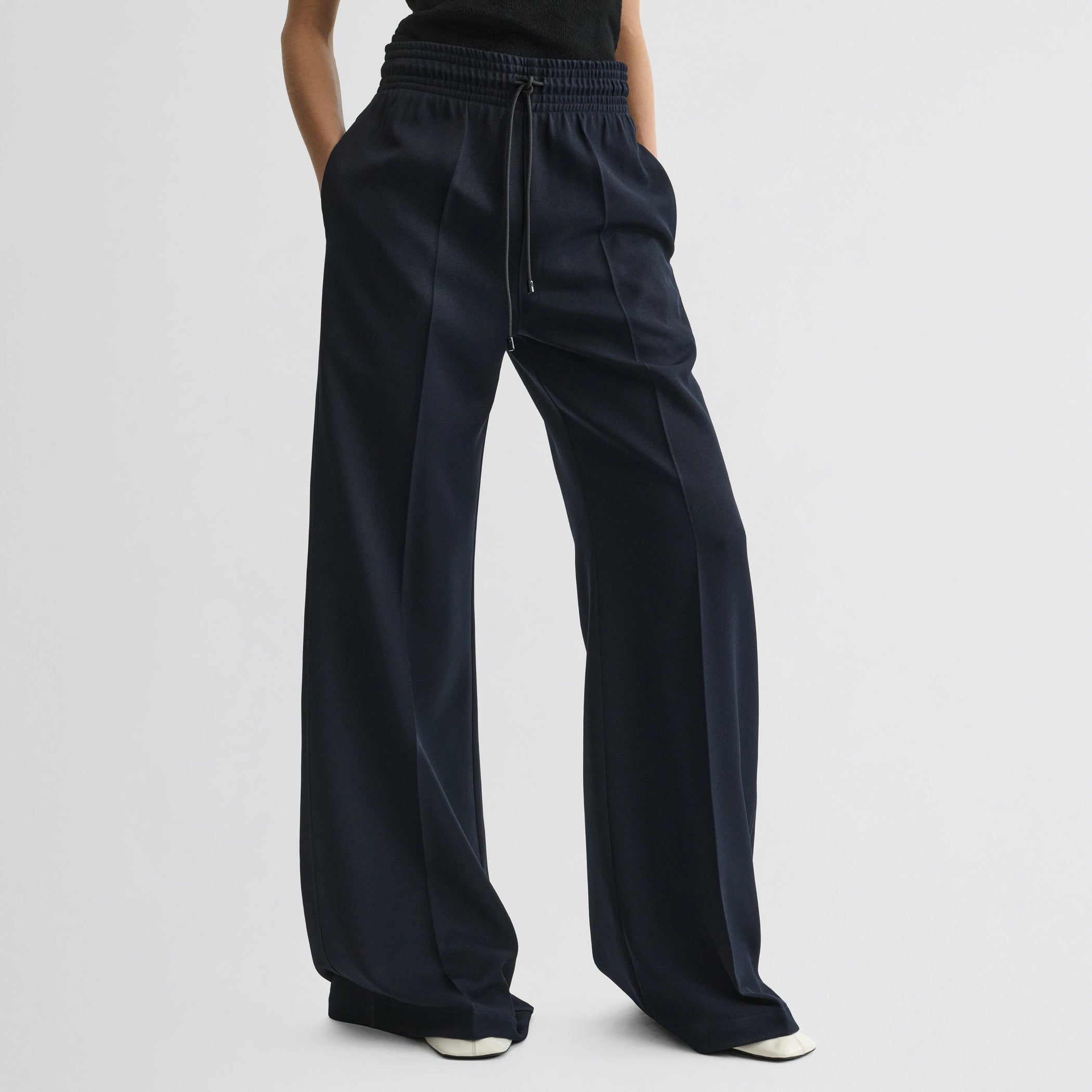 Front view of model wearing track trousers in navy polyester.
