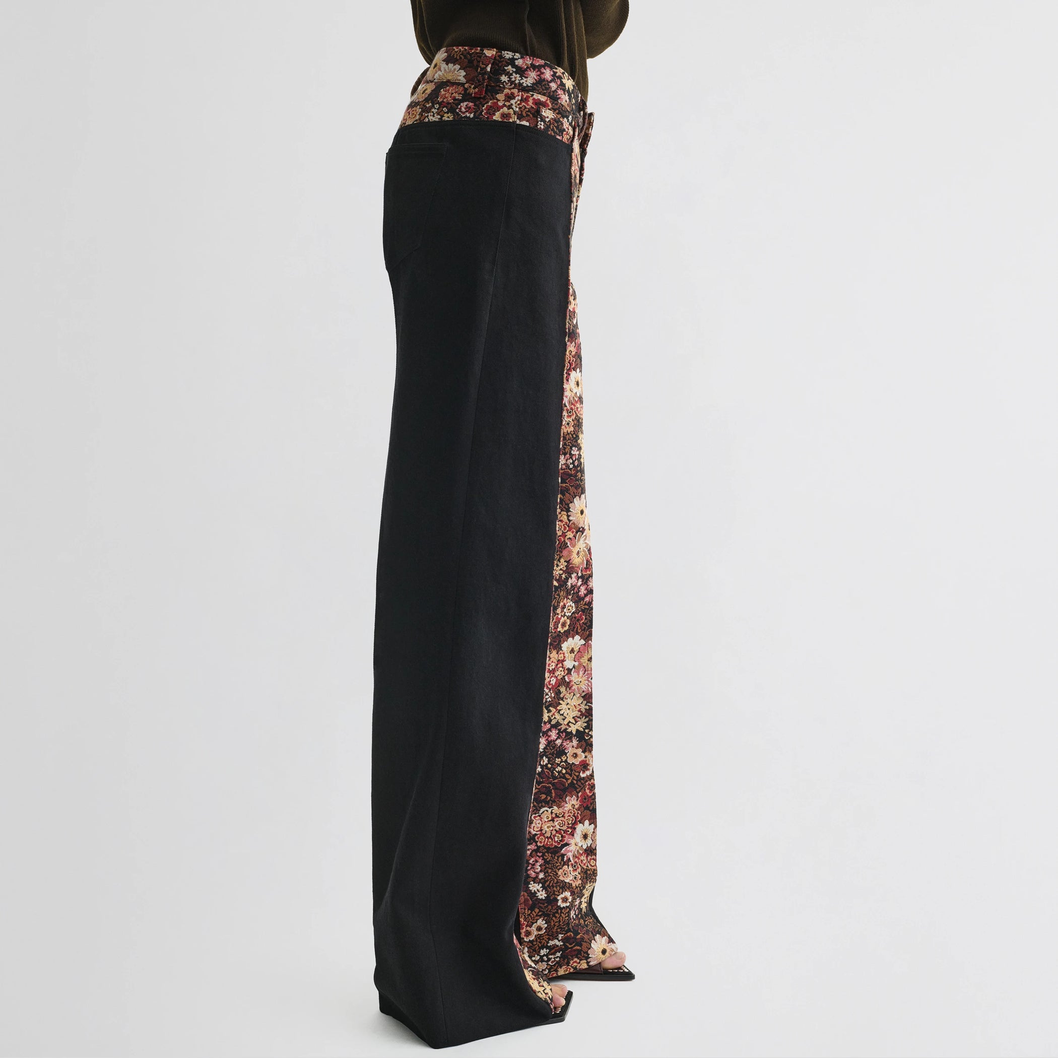 Side view of model wearing tapestry trousers in black cotton.