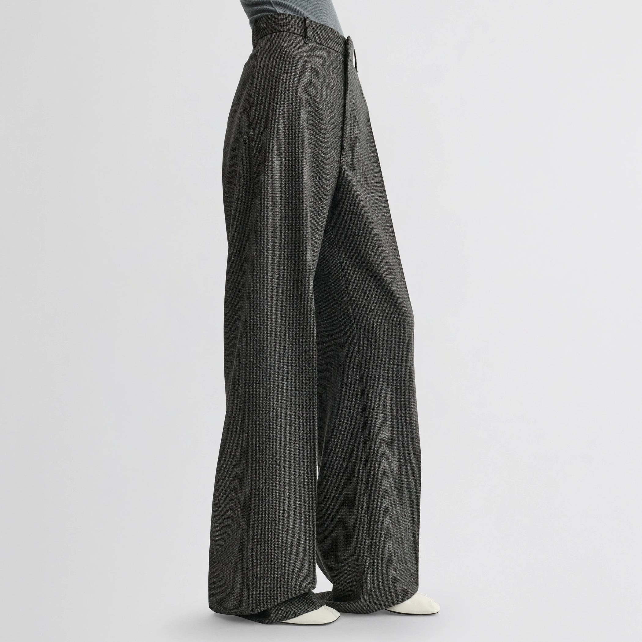 Side view of model wearing zip trousers in green bronze wool.