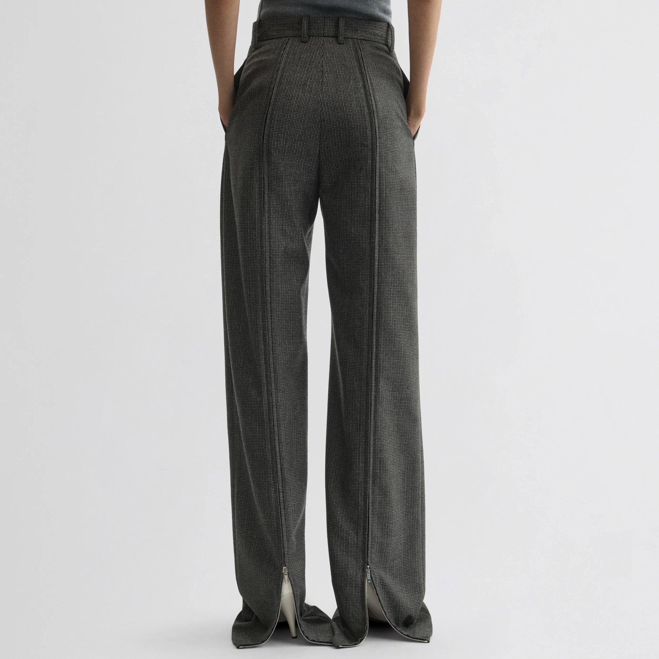 Back view of model wearing zip trousers in green bronze wool.
