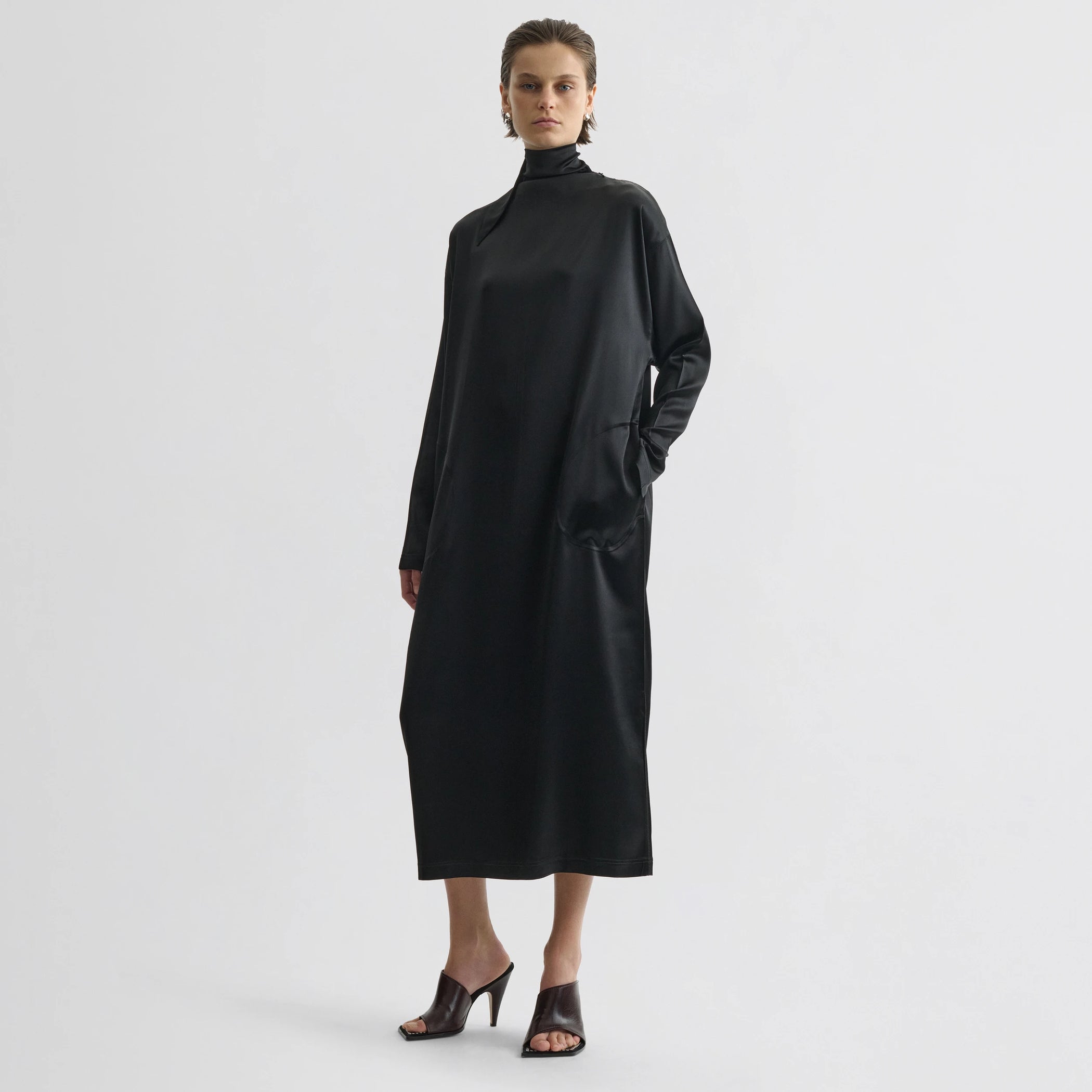 Front view of model wearing liquid high neck dress in black silk.