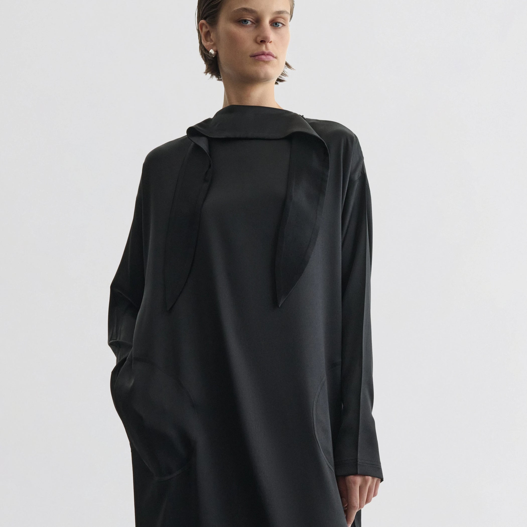 Front view of model wearing liquid high neck dress in black silk.