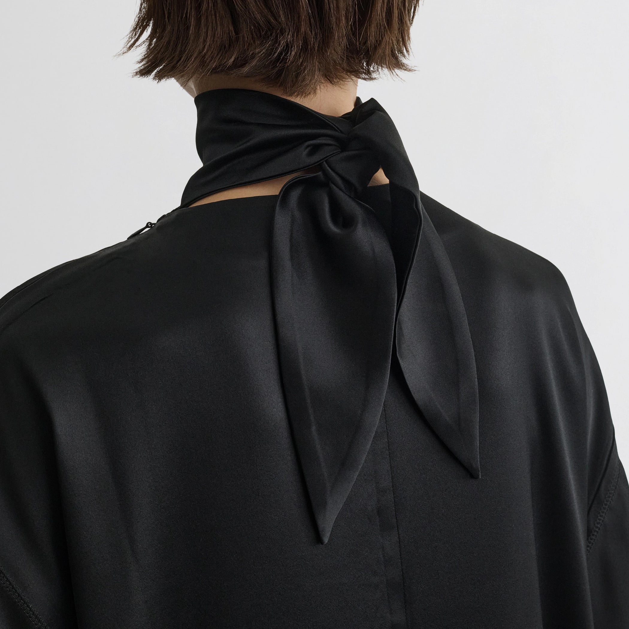 Close up detail view of liquid high neck dress in black silk.