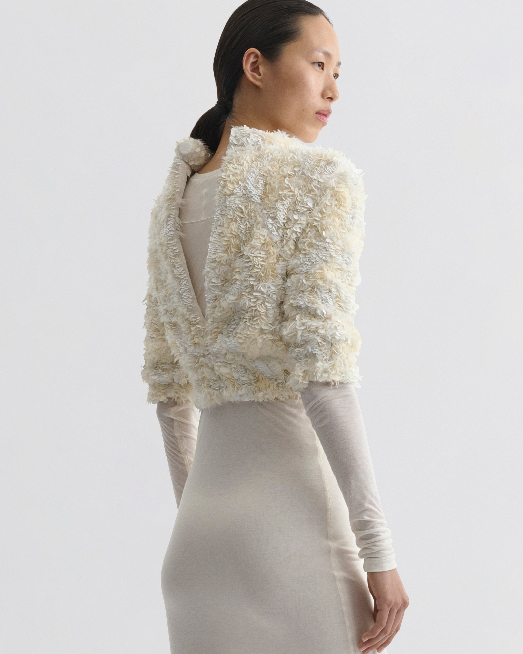 Back view of model wearing CLUSTERED SEQUIN DRESS in ivory jersey