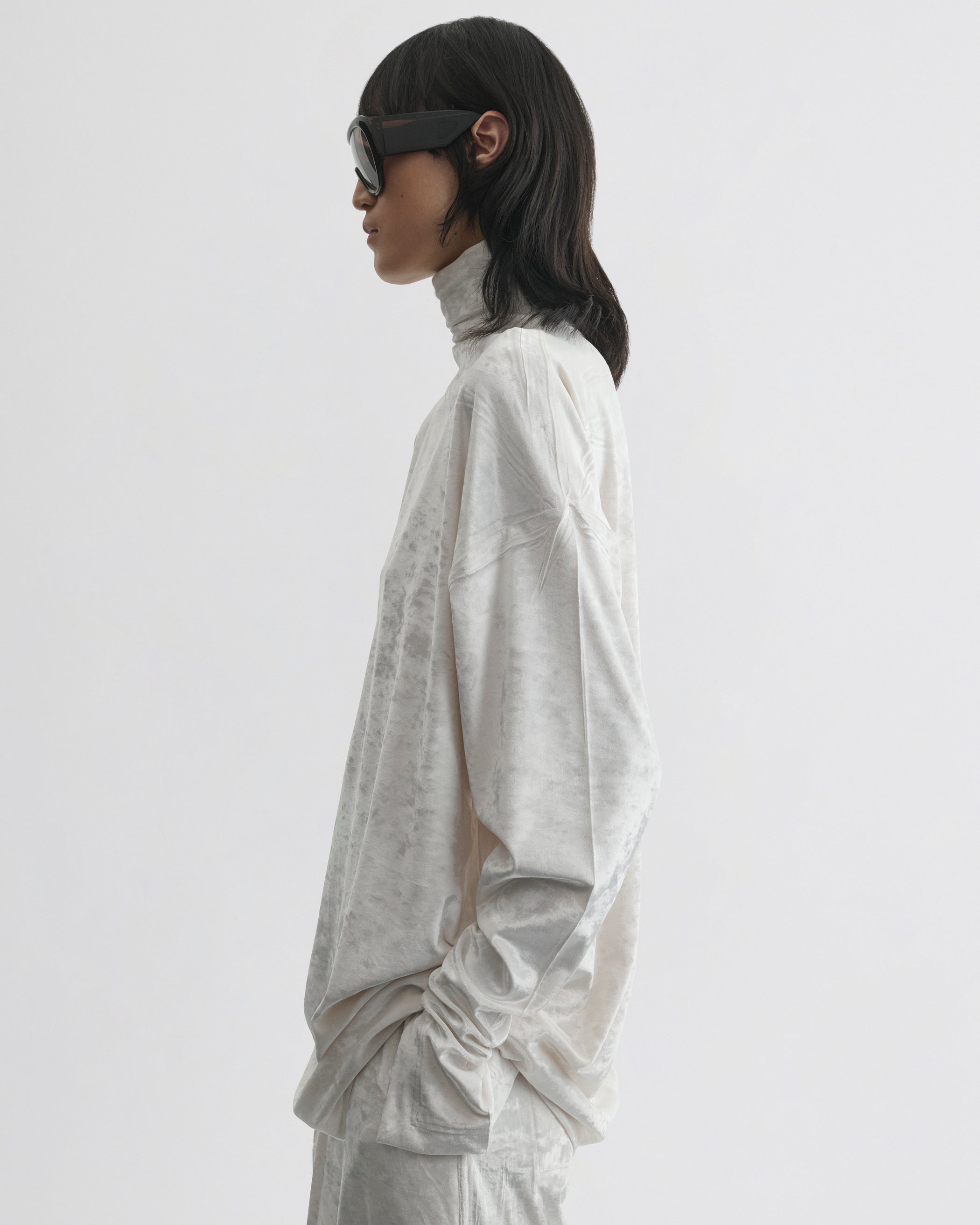 Side view of model wearing LIQUID HIGH NECK TOP in white crushed velvet