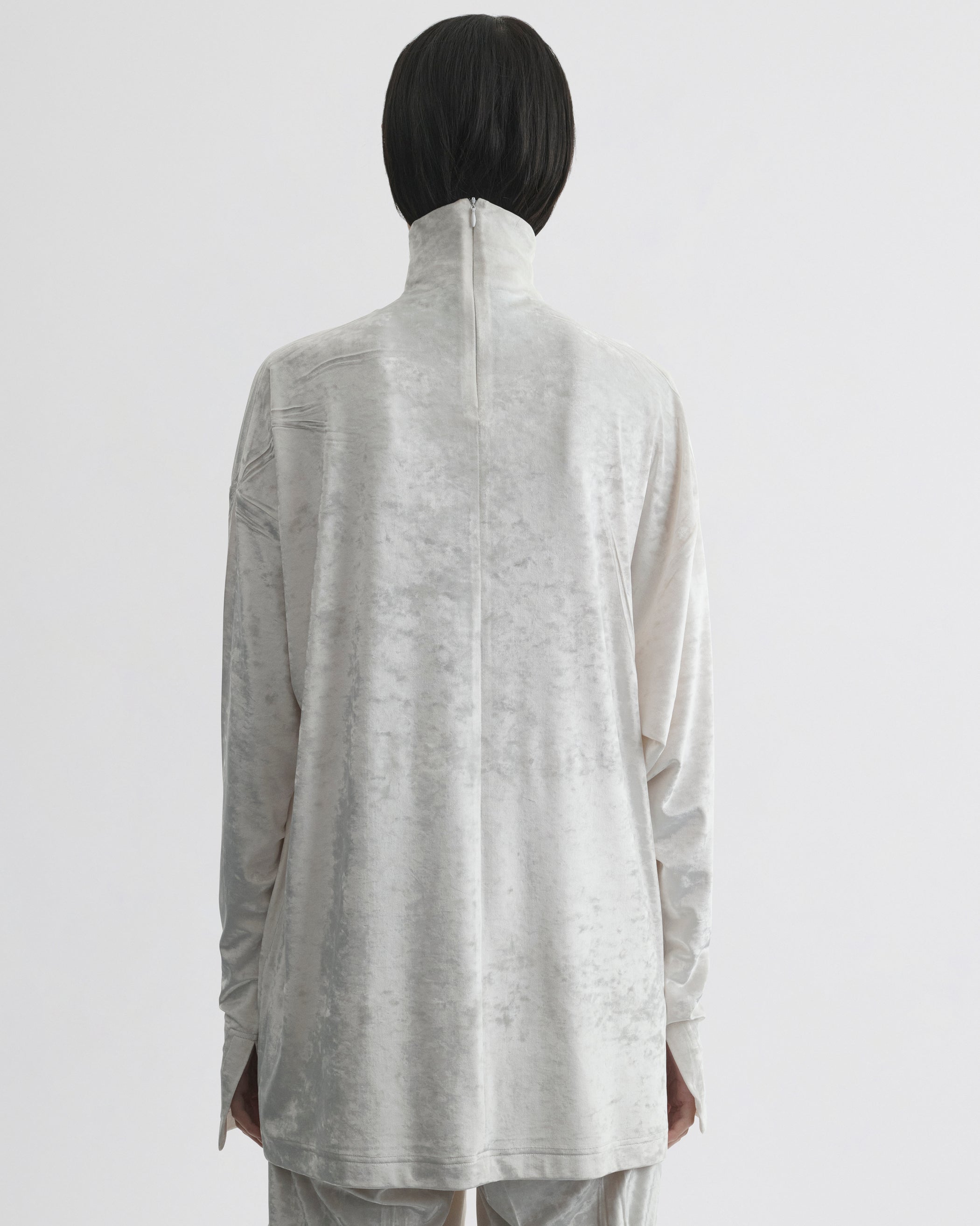 Back view of model wearing LIQUID HIGH NECK TOP in white crushed velvet