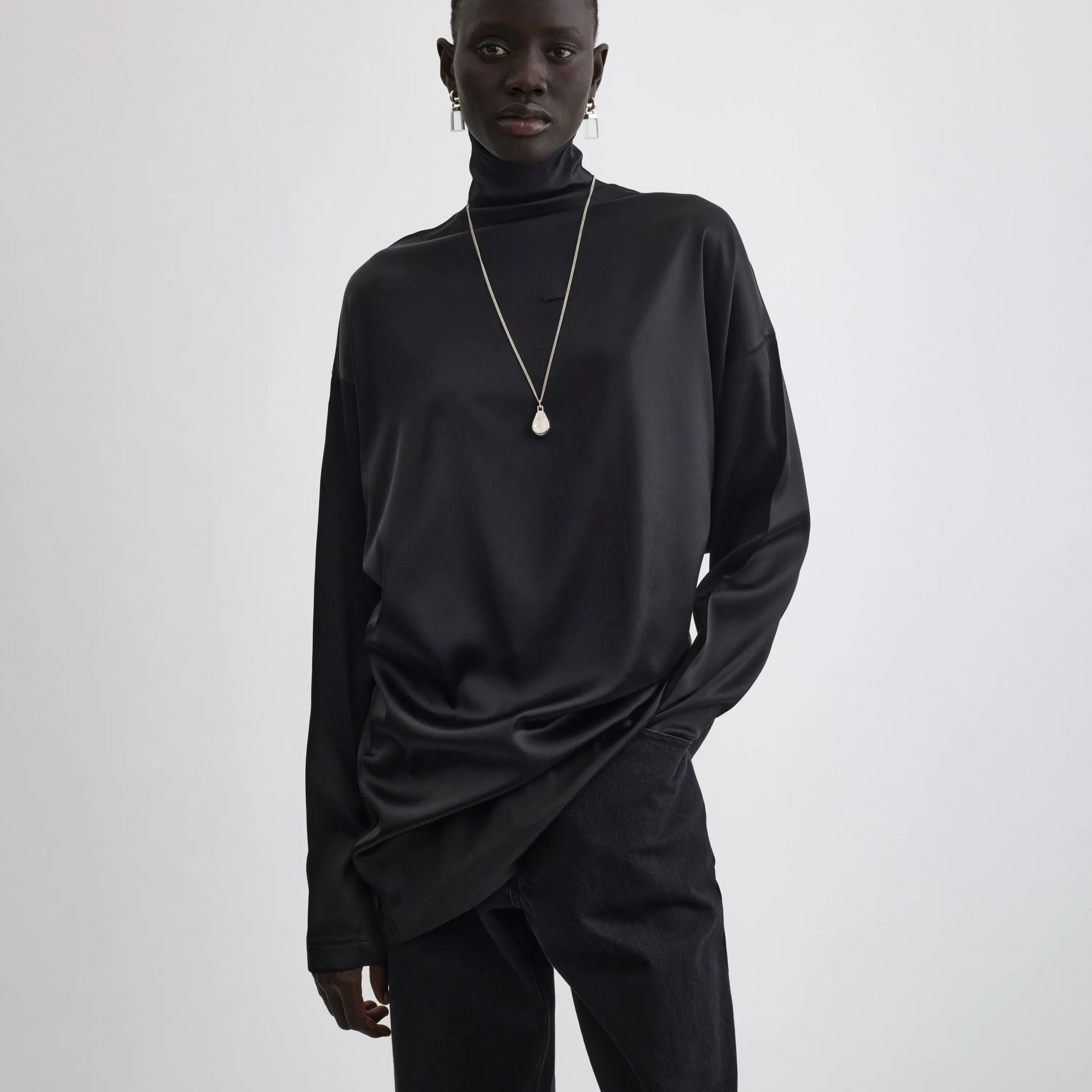 Front view of model wearing liquid high neck top in black.