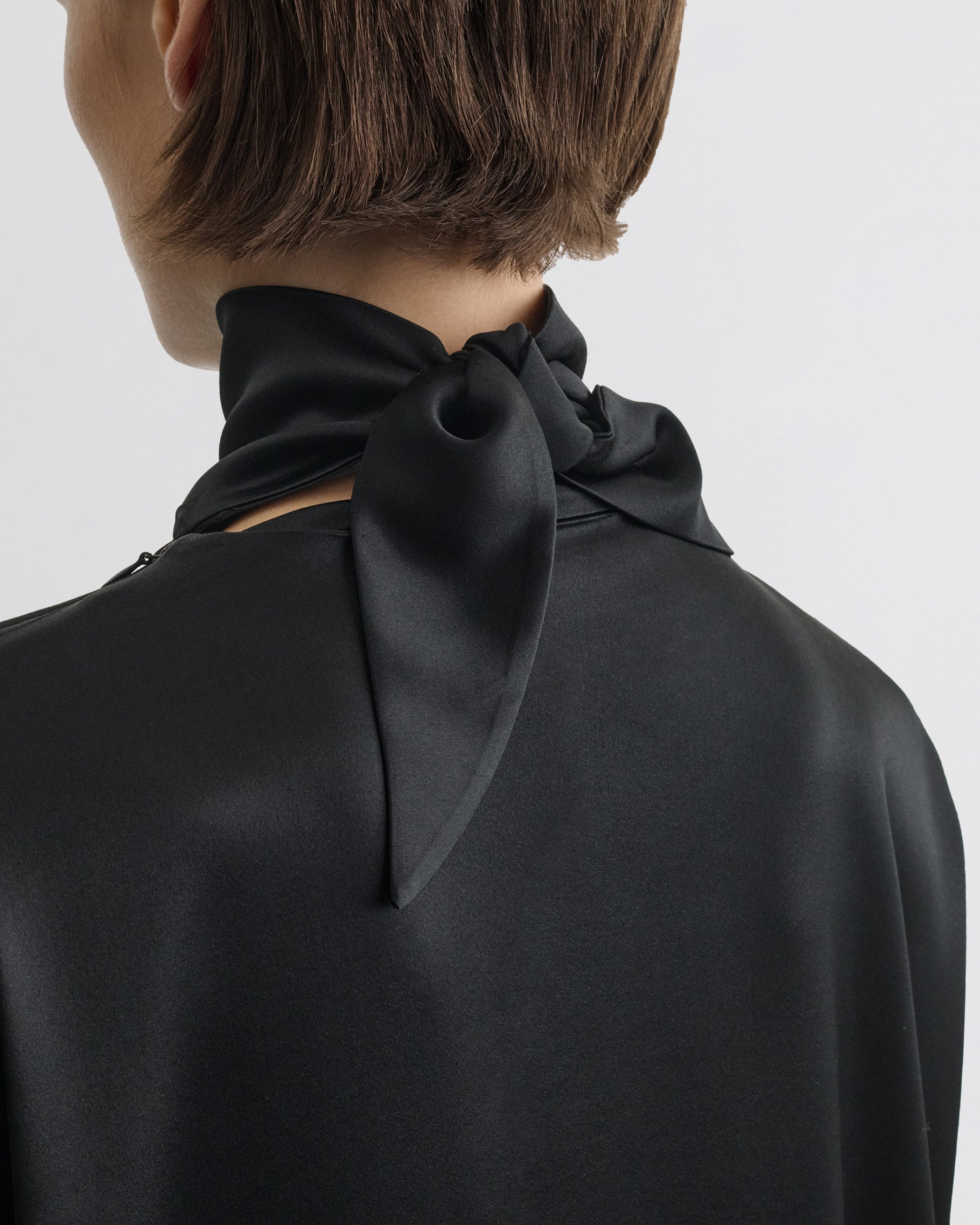 Back detail view of model wearing LIQUID KNOT COLLAR TOP in black silk