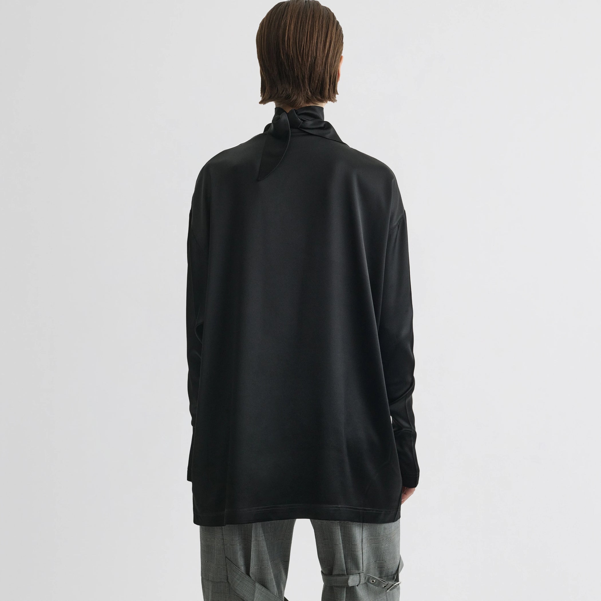 Back view of model wearing liquid knot collar top in black silk.