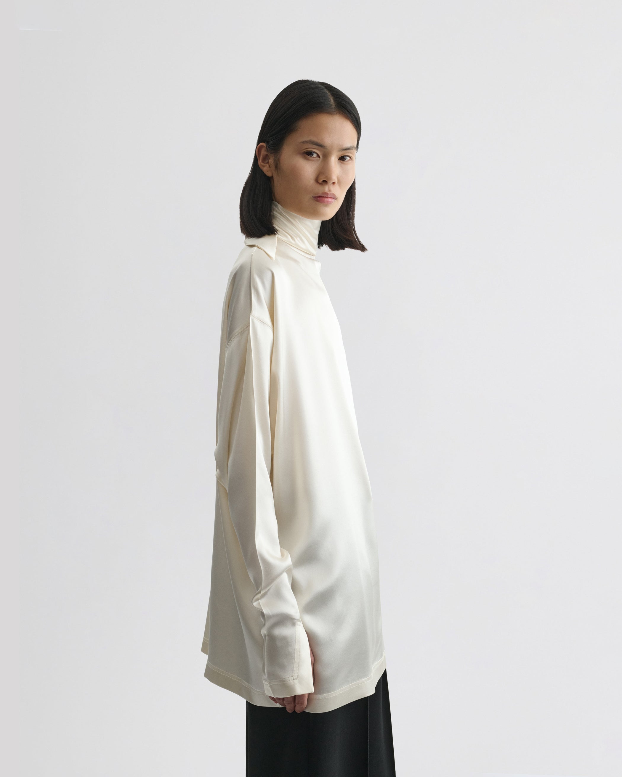 Side view of model wearing LIQUID KNOT COLLAR TOP in cream silk