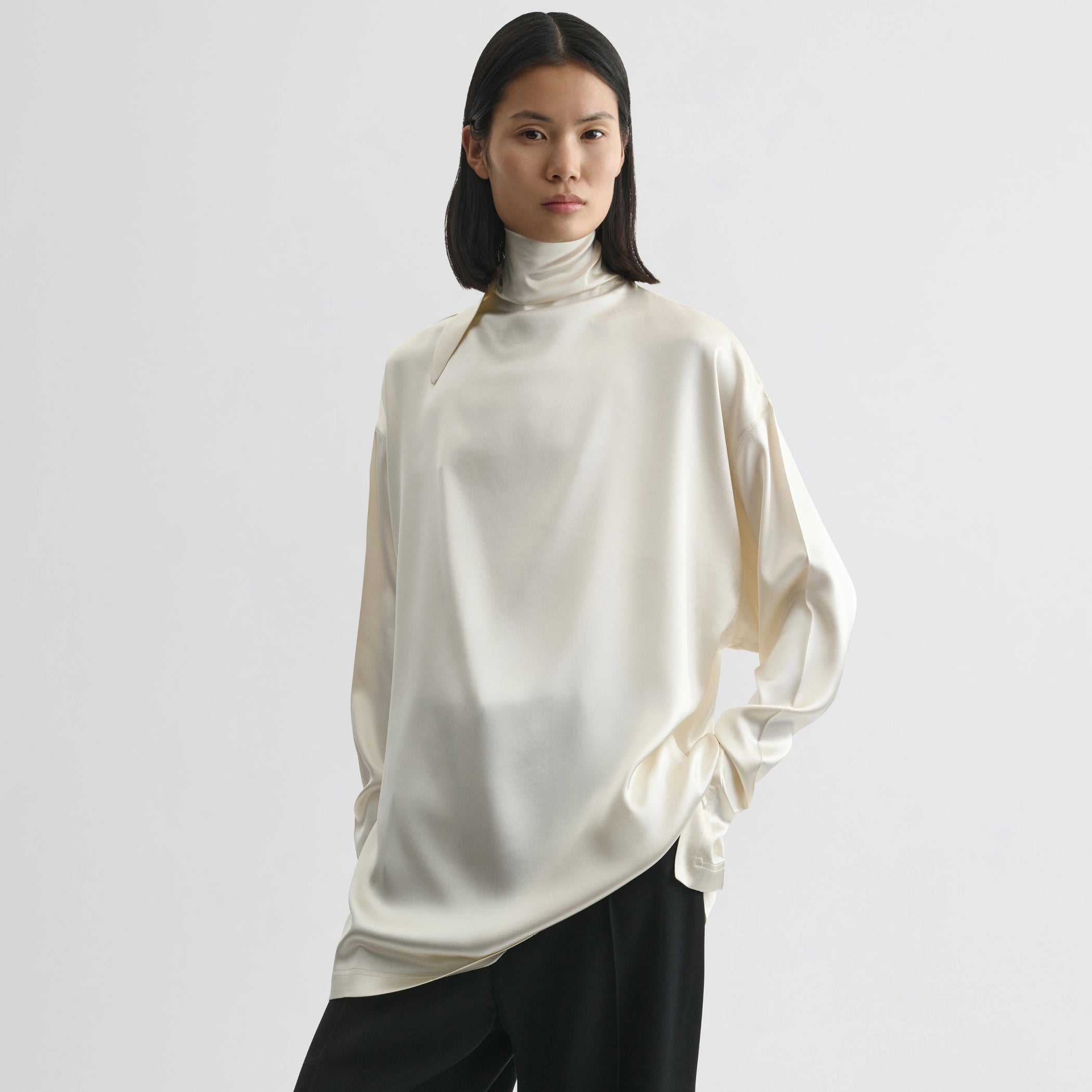 Front view of model wearing liquid knot collar top in cream silk.