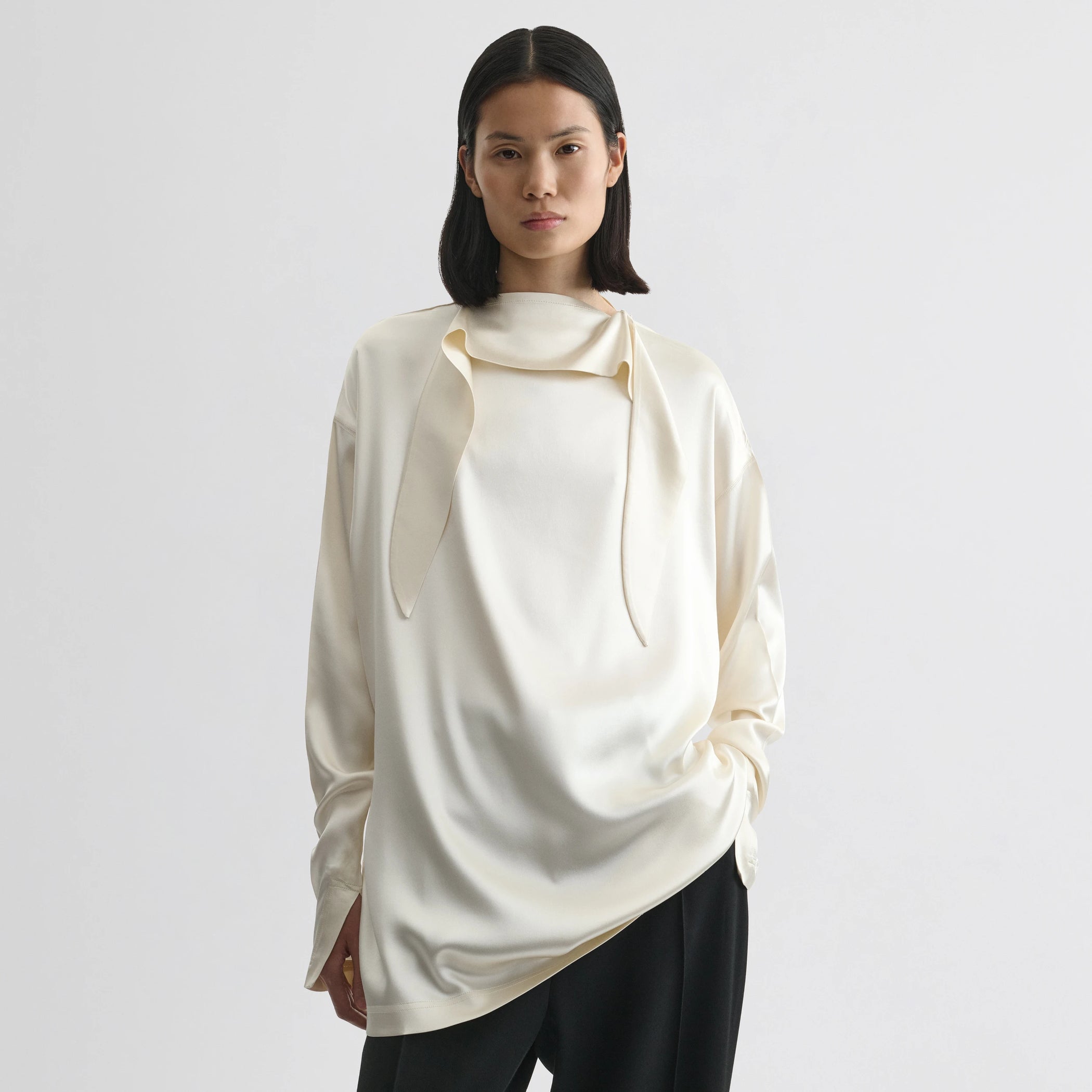 Front view of model wearing liquid knot collar top in cream silk.