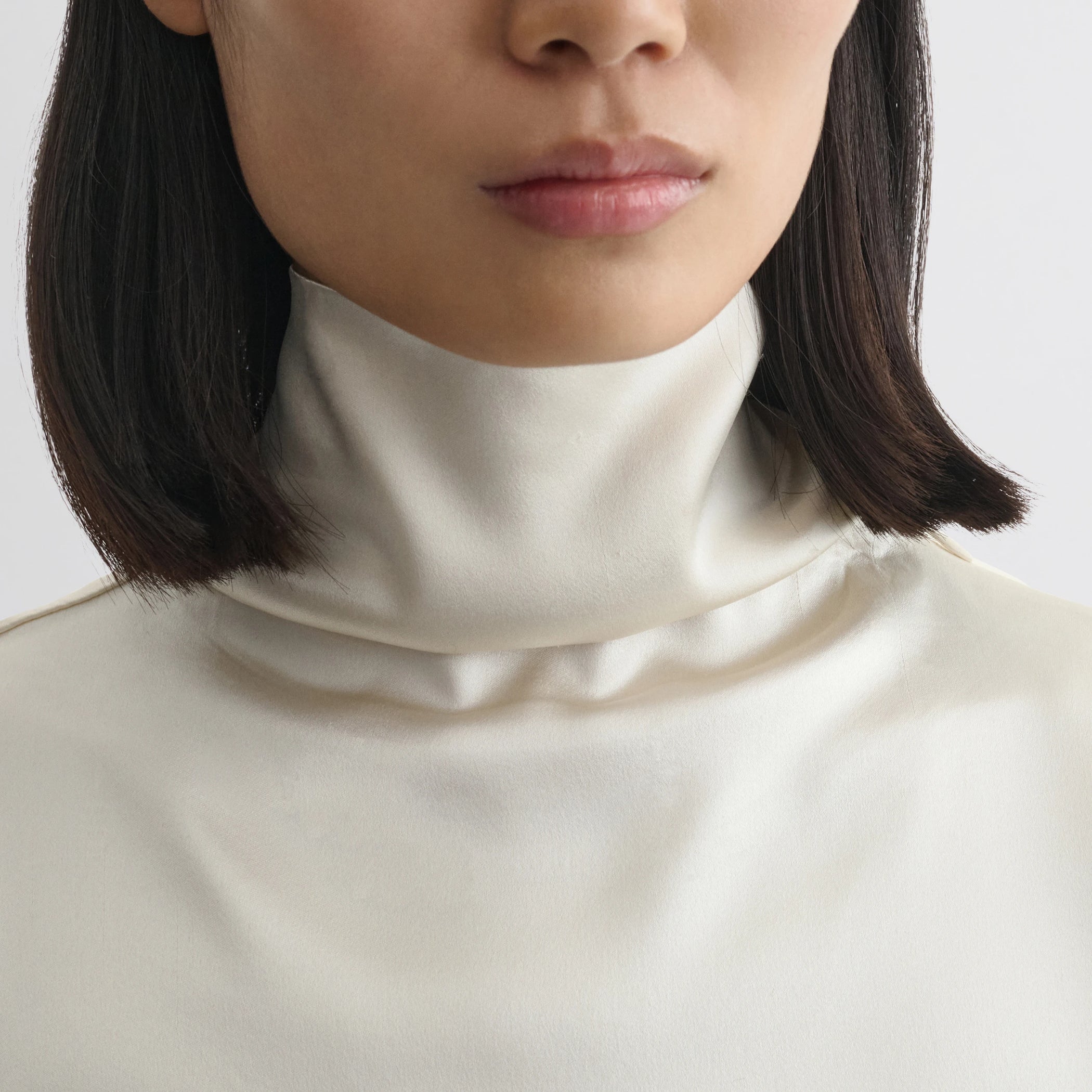 Close up detail view of liquid knot collar top in cream silk.