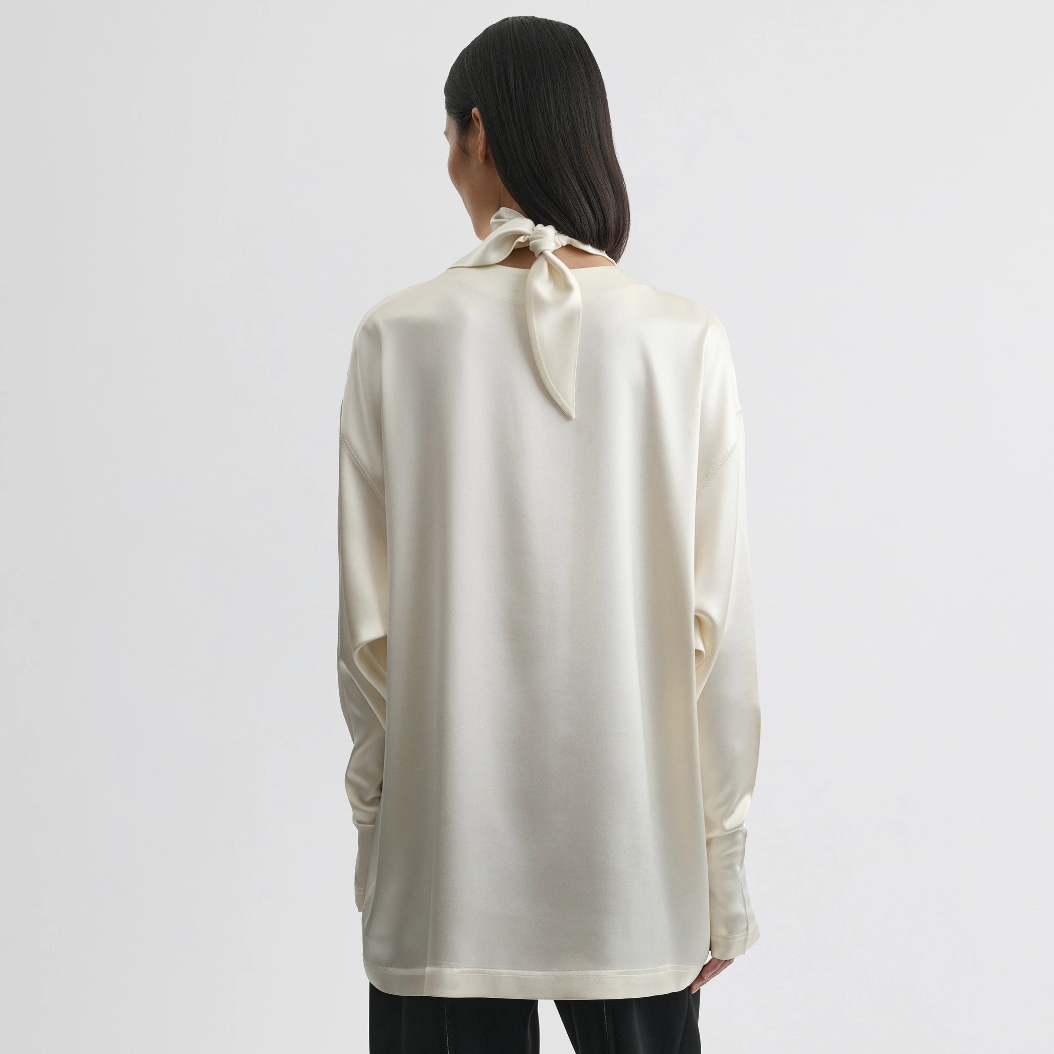 Back view of model wearing liquid knot collar top in cream silk.