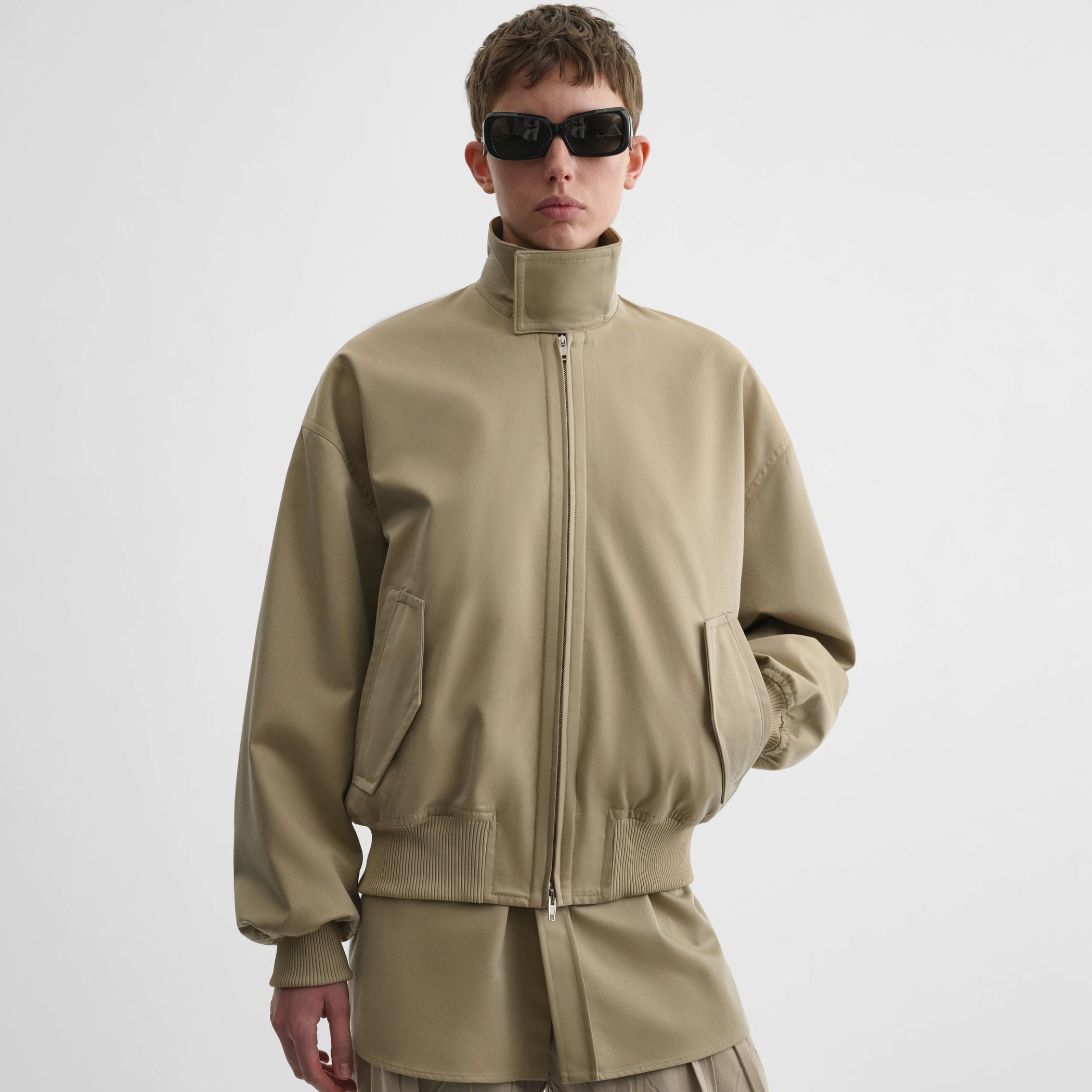 Front view of model wearing golf jacket in trench cotton.